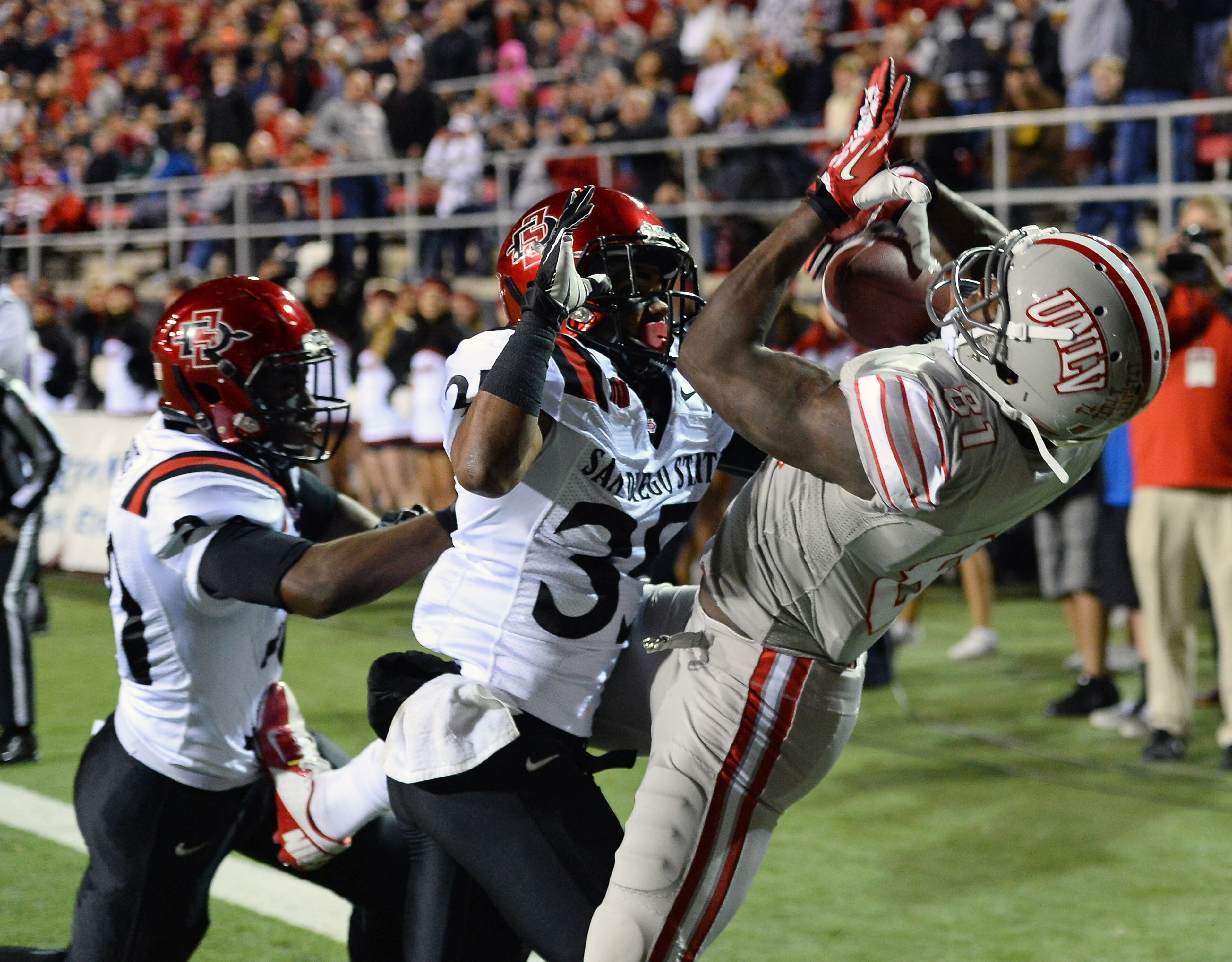 Devante Davis (81) of the UNLV Rebels catches a 5-yard touchdown pass in the end zone against King Holder (35) and Nat Berhe (20) of the San Diego State Aztecs during their game at Sam Boyd Stadium on November 30, 2013 in Las Vegas. (Photo by Ethan Miller/Getty Images)