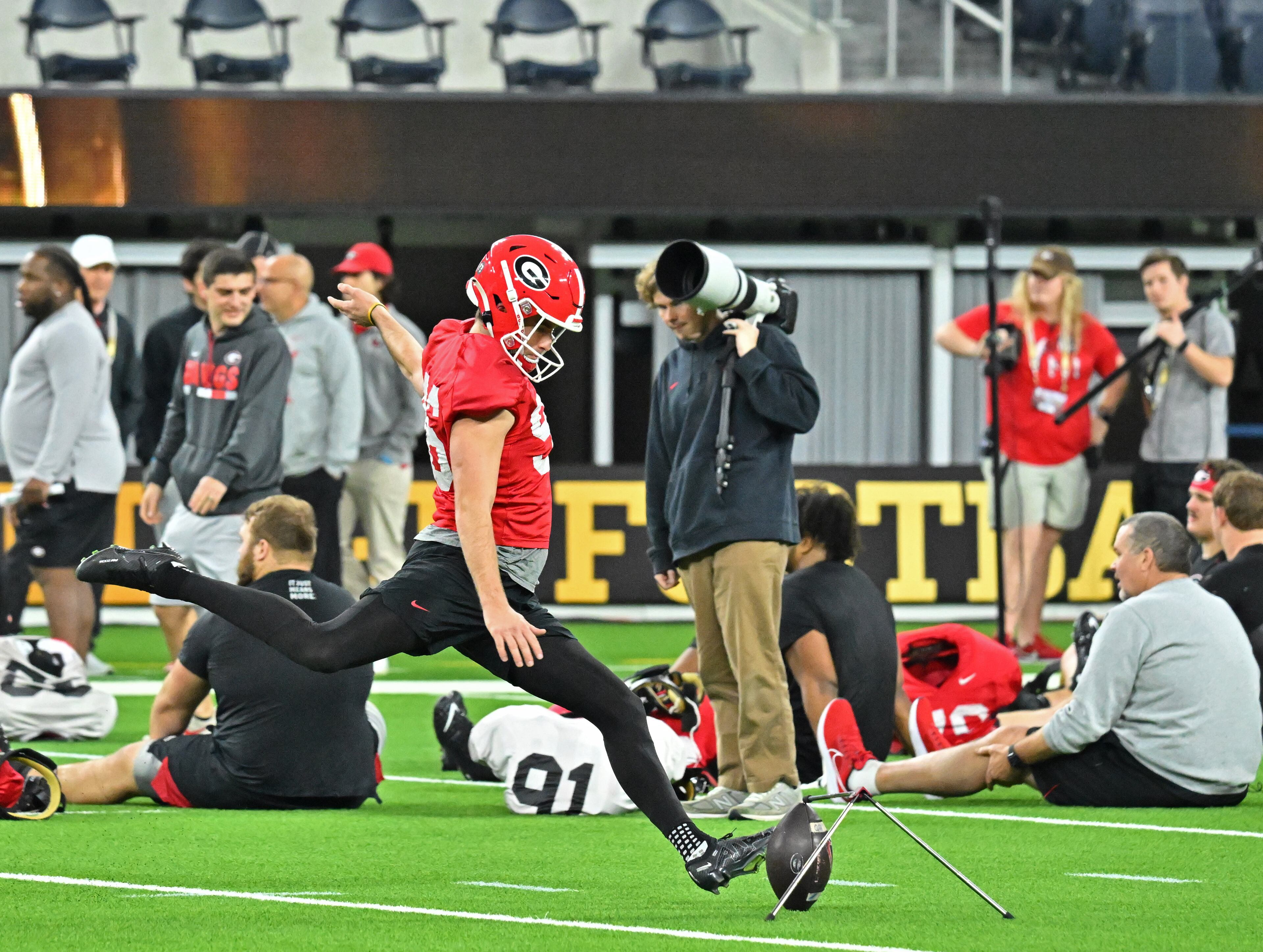 Georgia's place kicker Jack Podlesny hits a ball as other players participate in a yoga session during the media viewing portion of practice at SoFi Stadium ahead of the national championship NCAA College Football Playoff game between Georgia and TCU, Saturday, Jan. 7, 2023, in Los Angeles. (Hyosub Shin / Hyosub.Shin@ajc.com)