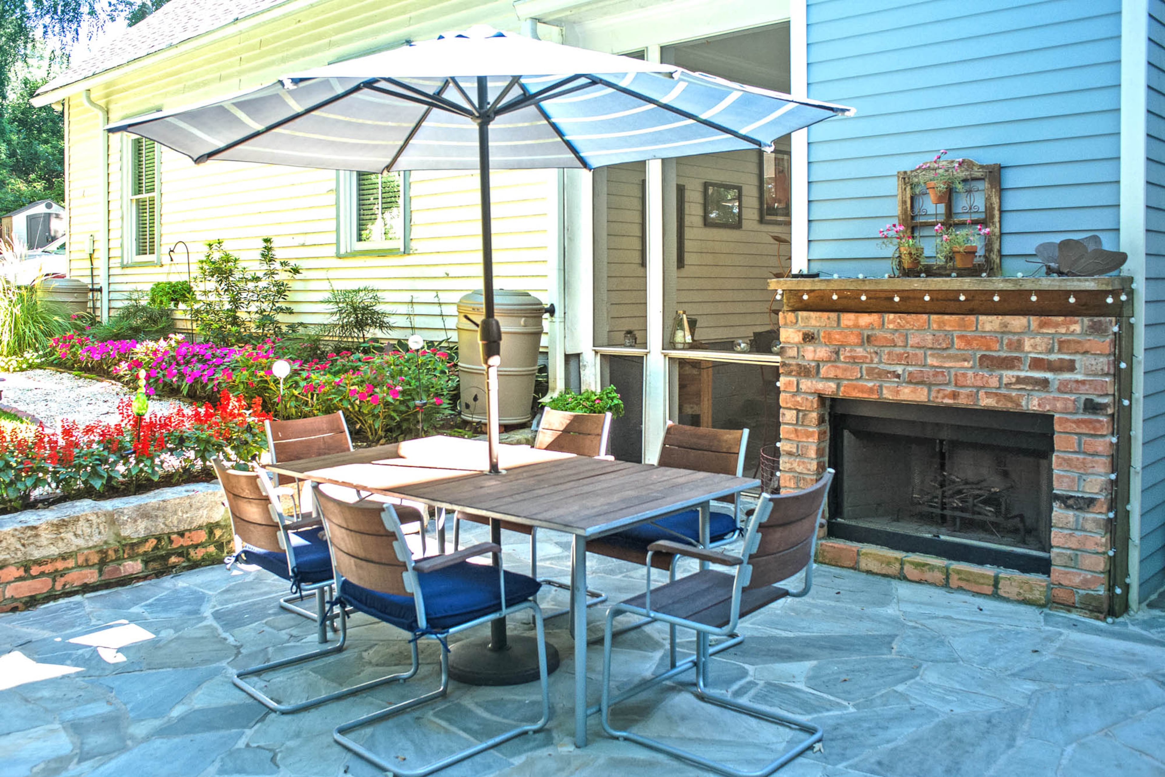 The flagstone patio, which has repurposed granite and brick from the foundation and chimney used for its perimeter, includes room for a teak dining set. The double-sided fireplace connects to the screened patio.(Christopher Oquendo Photography)
