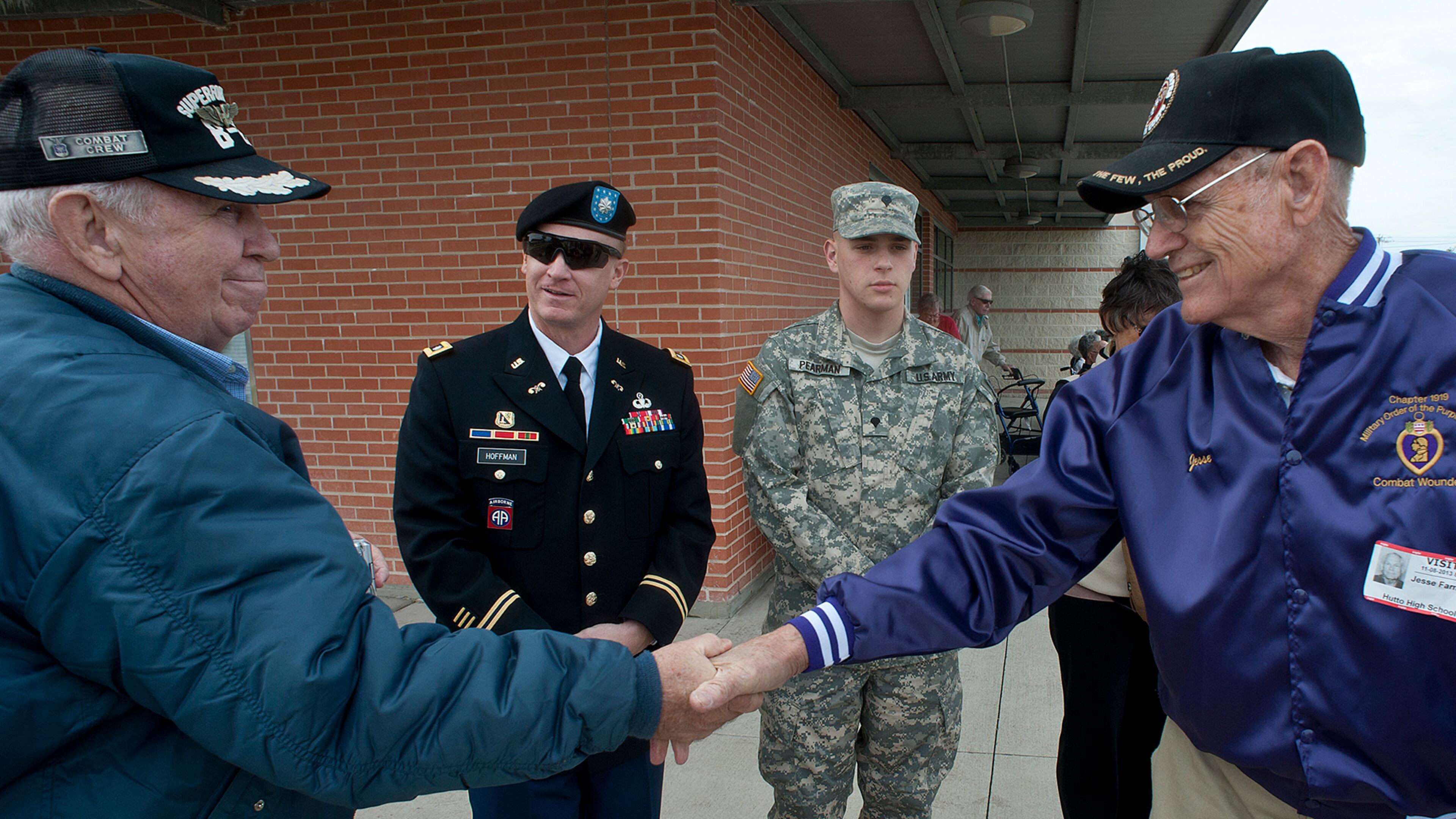 Korean War veteran Bud Farrell, left, and World War II veteran Jim Farmer shake hands Friday at Hutto High School in Hutto, Texas. The school dedicated the day to honoring veterans.