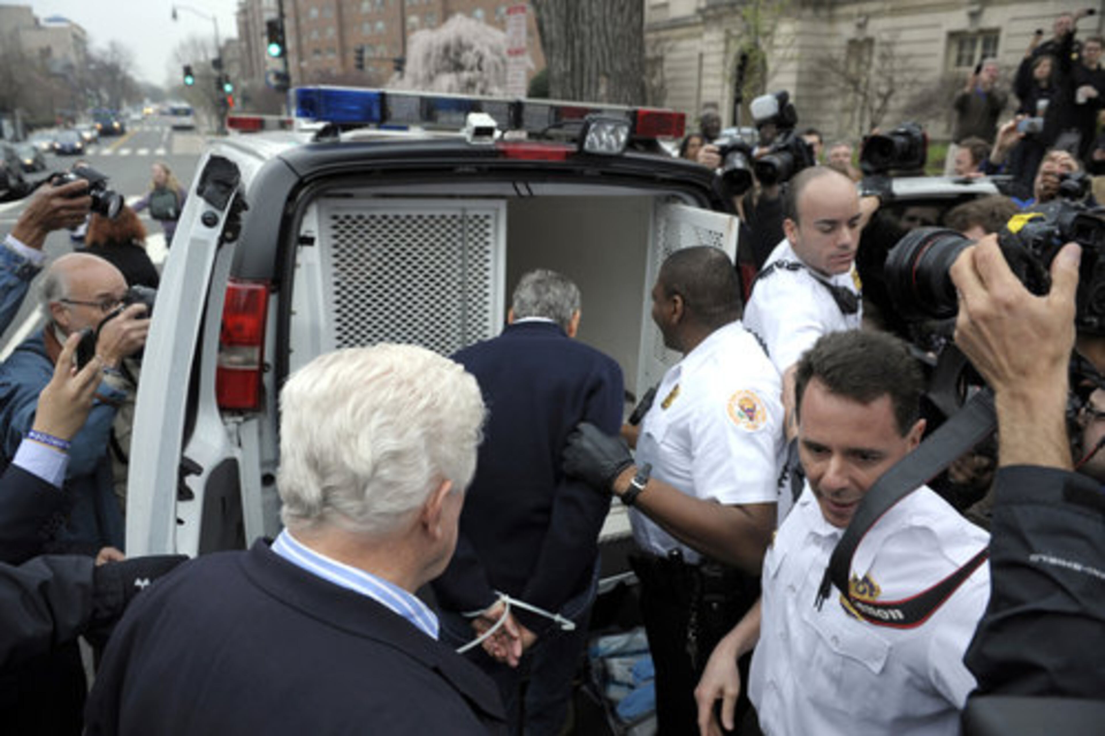 Actor George Clooney, center, followed by Rep. Jim Moran, D-Va, lower left, are placed into a police vehicle after being arrested.