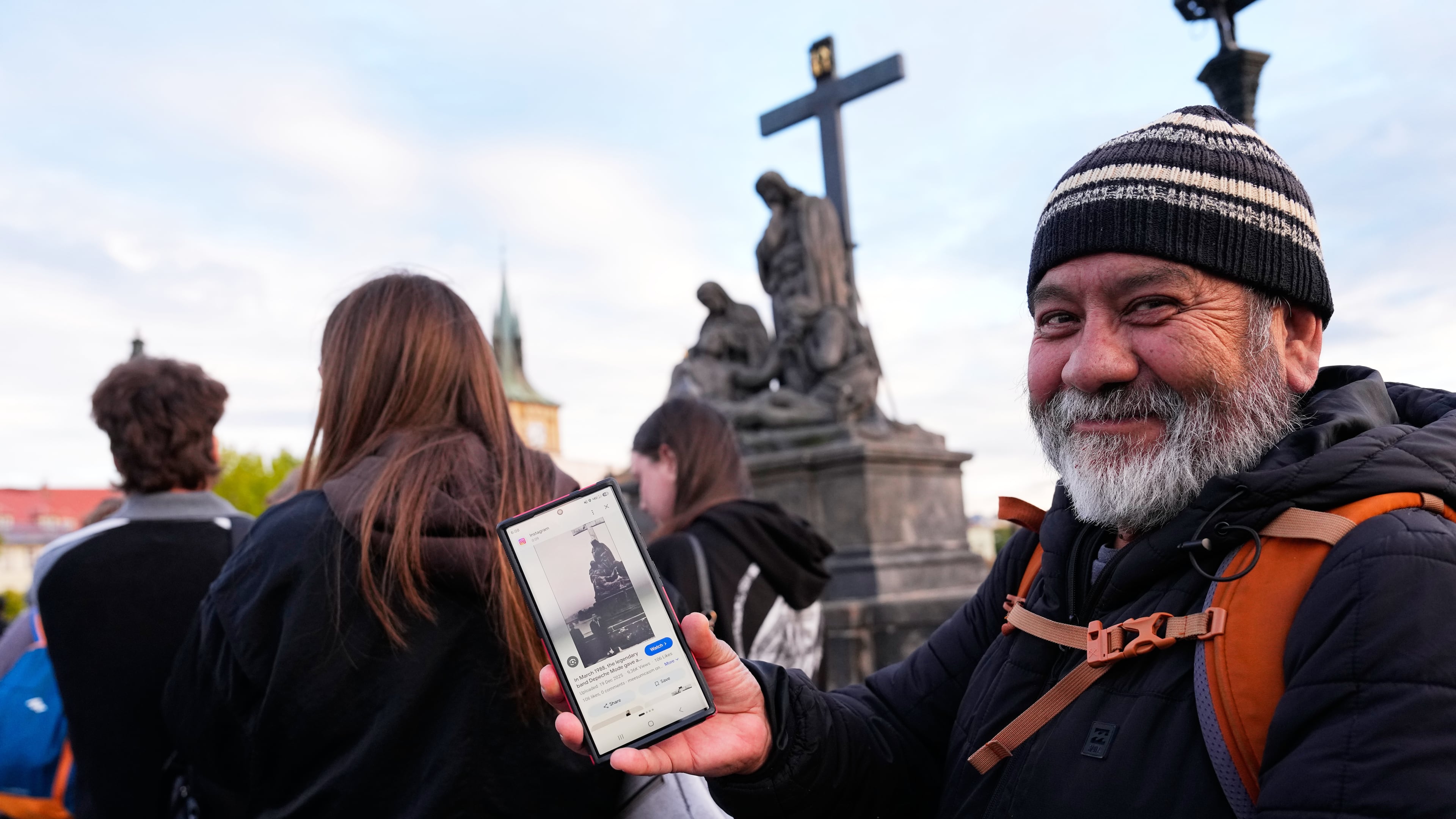 Jorge Sanchez from Los Angeles displays a famous photo of two members of Depeche Mode, taken by Dutch photographer Anton Corbijn in 1988, as he waits in line to recreate this image by the Pieta statue at the Charles Bridge in Prague, Czech Republic, Thursday, Sept. 24, 2026. (AP Photo/Petr David Josek)
