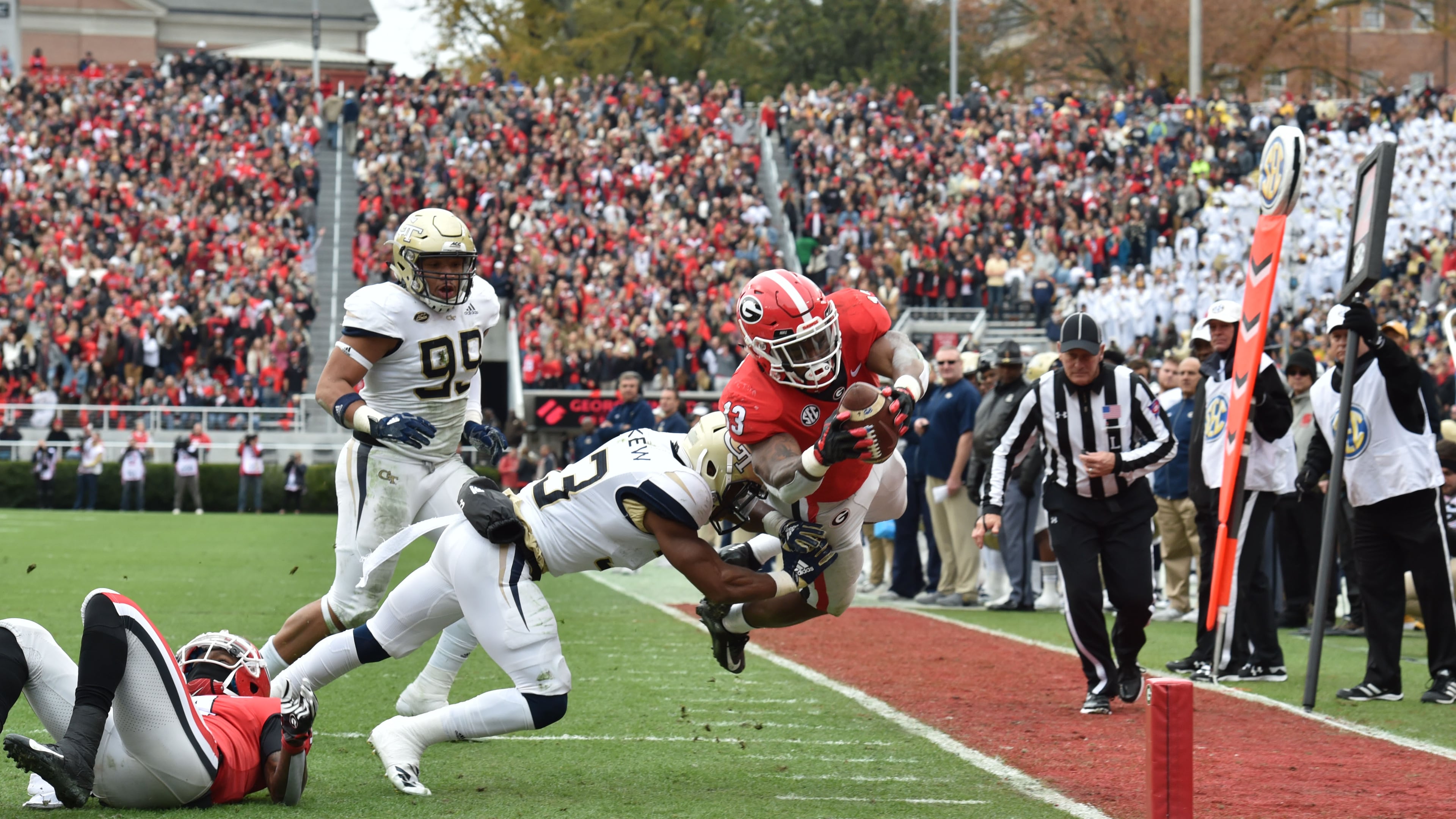 Georgia running back Elijah Holyfield (13) falls into the endzone past Georgia Tech defensive back Jaytlin Askew (33) for a touchdown during the first half in a NCAA college football game at Sanford Stadium on Saturday, November 24, 2018. HYOSUB SHIN / HSHIN@AJC.COM
