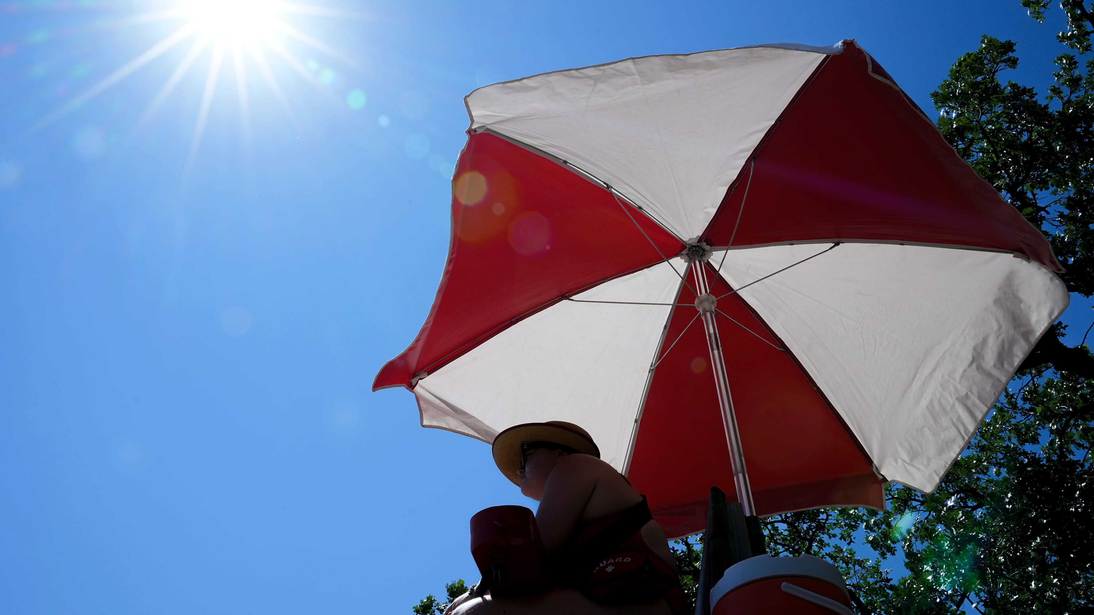 The sun beams down on a lifeguard while she watches over a beach at Lake Harriet during an extreme heat warning, Monday, July 13, 2026, in Minneapolis. (AP Photo/Ellen Schmidt)