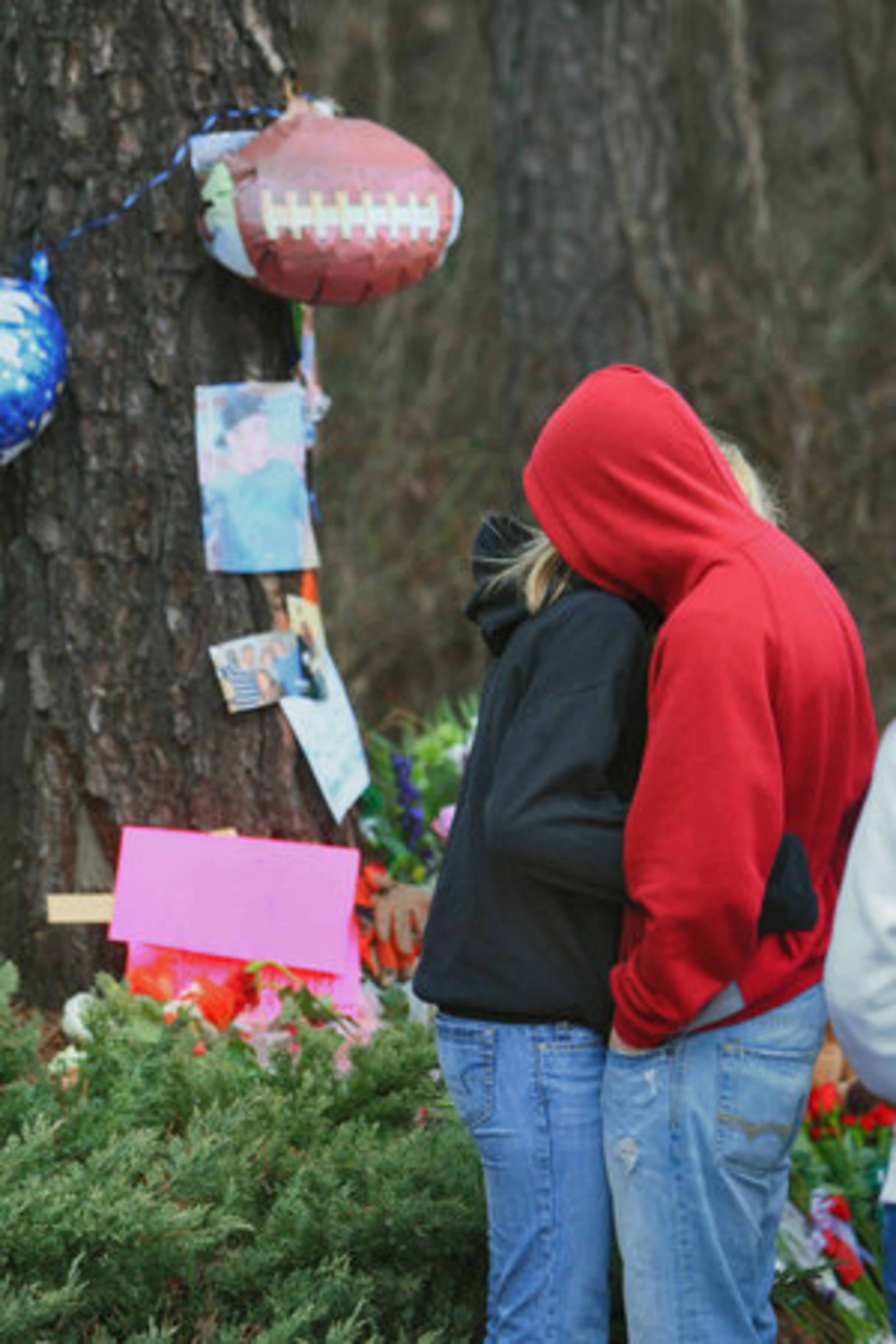 Friends Stephaine Roembke (left) and Trent Benson, both 17, embrace Monday morning as they remember Garrett Reed.