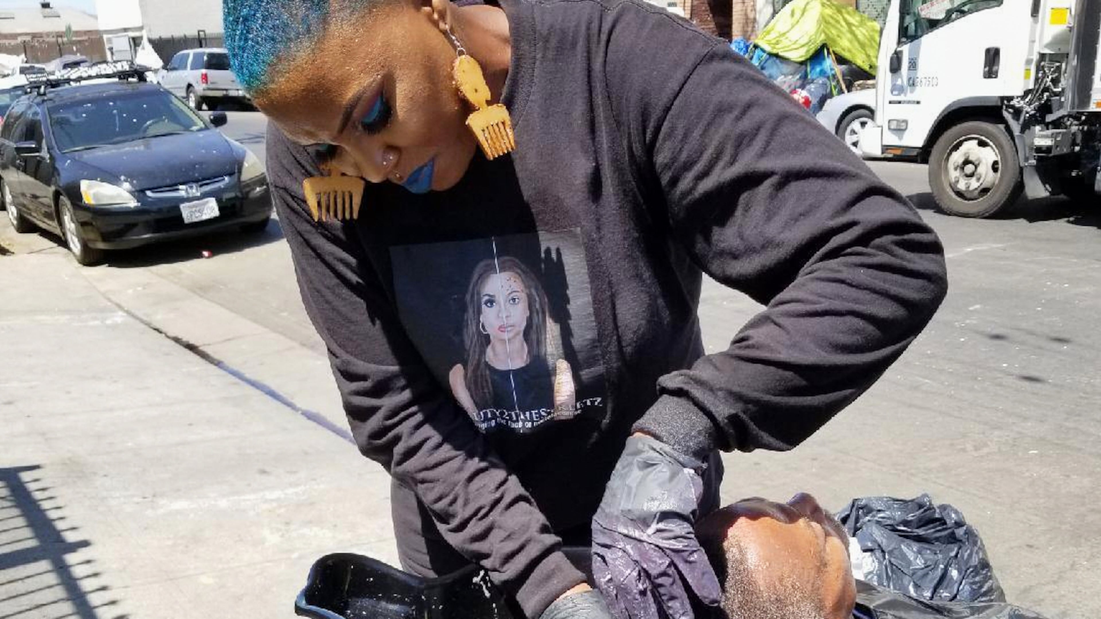 This photo provided by Melissa Acedera shows Shirley Raines washing a person's hair in Skid Row, 2018, in Los Angeles. (Melissa Acedera via AP)