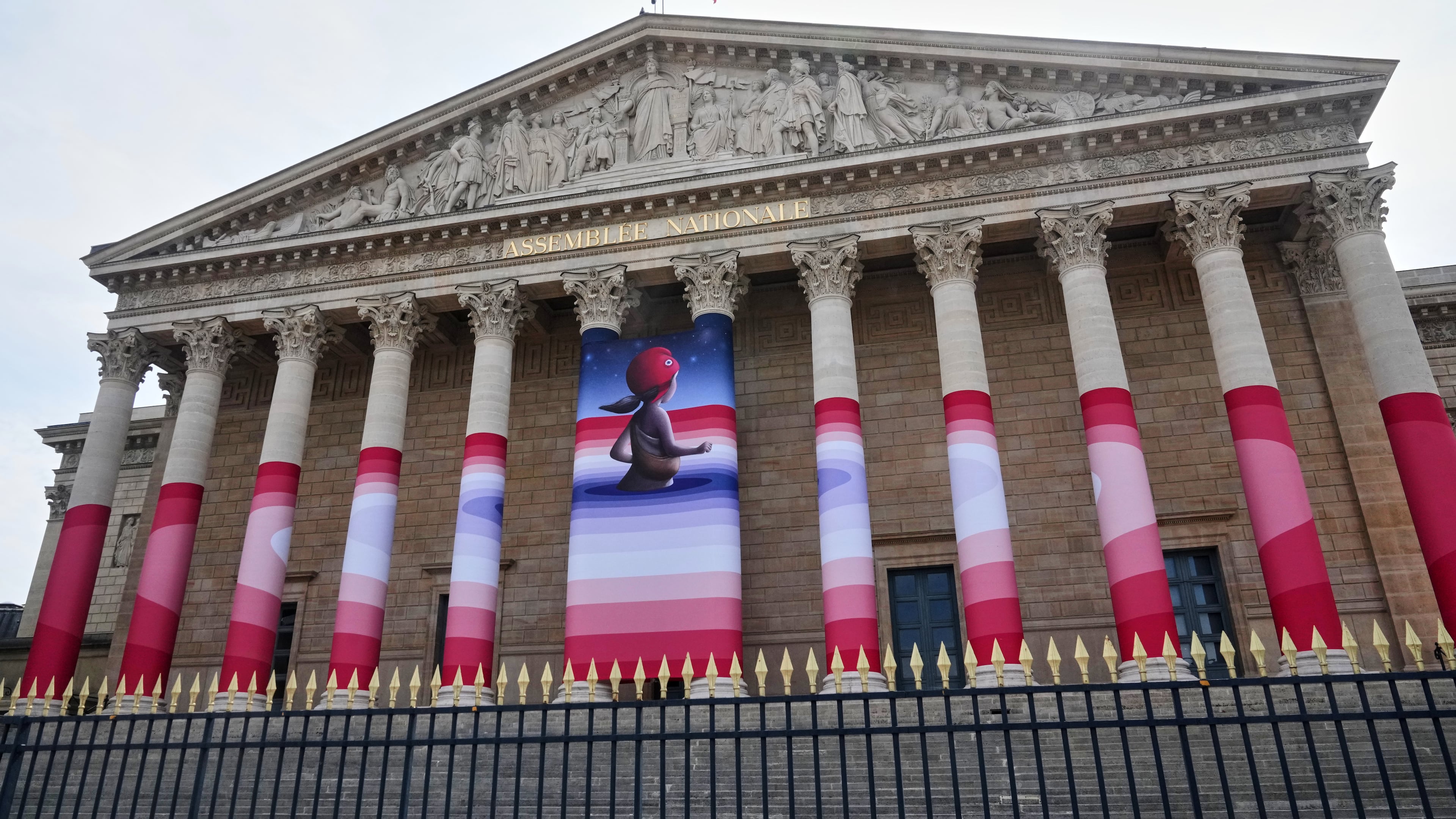 The French National Assembly is draped with the artwork "Marianne rêve" ("Marianne Dreams") by French street artist Seth, depicting Marianne the symbol of the French Republic, before lawmakers vote later on final approval of a bill allowing adults with incurable illnesses to receive lethal medication, in Paris, Wednesday, July 15, 2026. (AP Photo/Michel Euler)