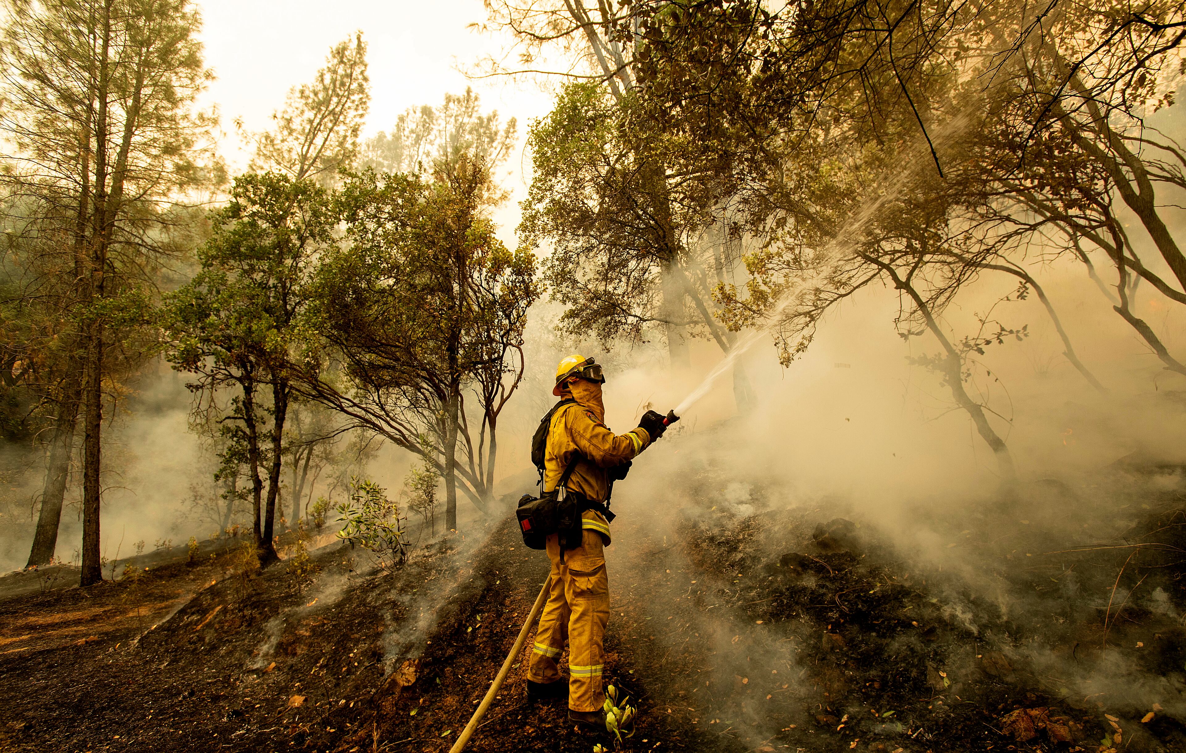 Firefighter Scott Brown sprays water on a backfire while battling the Carr Fire in Redding, Calif., on Saturday, July 28, 2018. (AP Photo/Noah Berger)