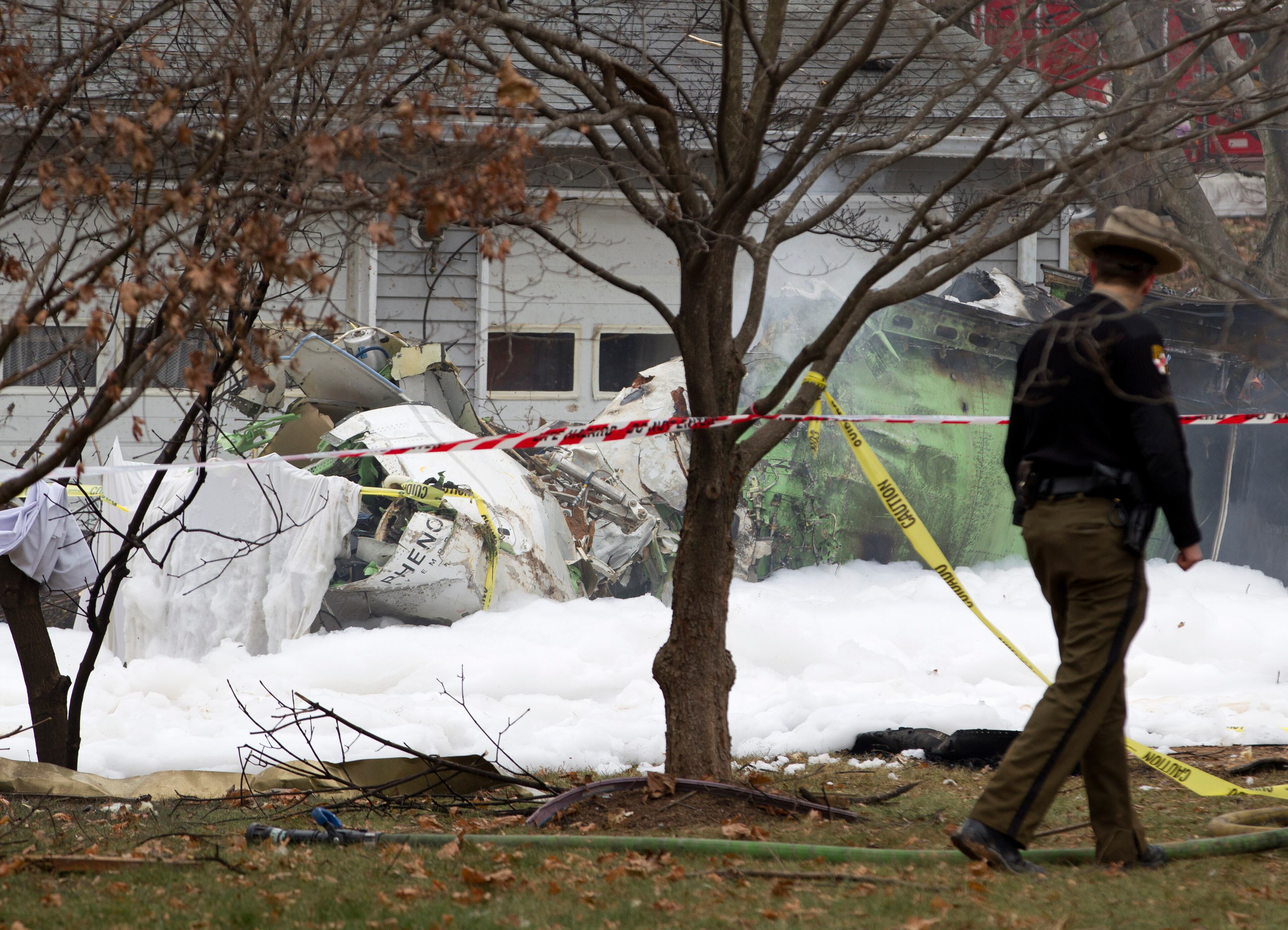 The wreckage of a small plane smolders in a house driveway after crashing in Gaithersburg, Md., Monday Dec. 8, 2014. The small, private jet has crashed into a house in Maryland's Montgomery County, and a fire official says multiple people were killed. (AP Photo/Jose Luis Magana)