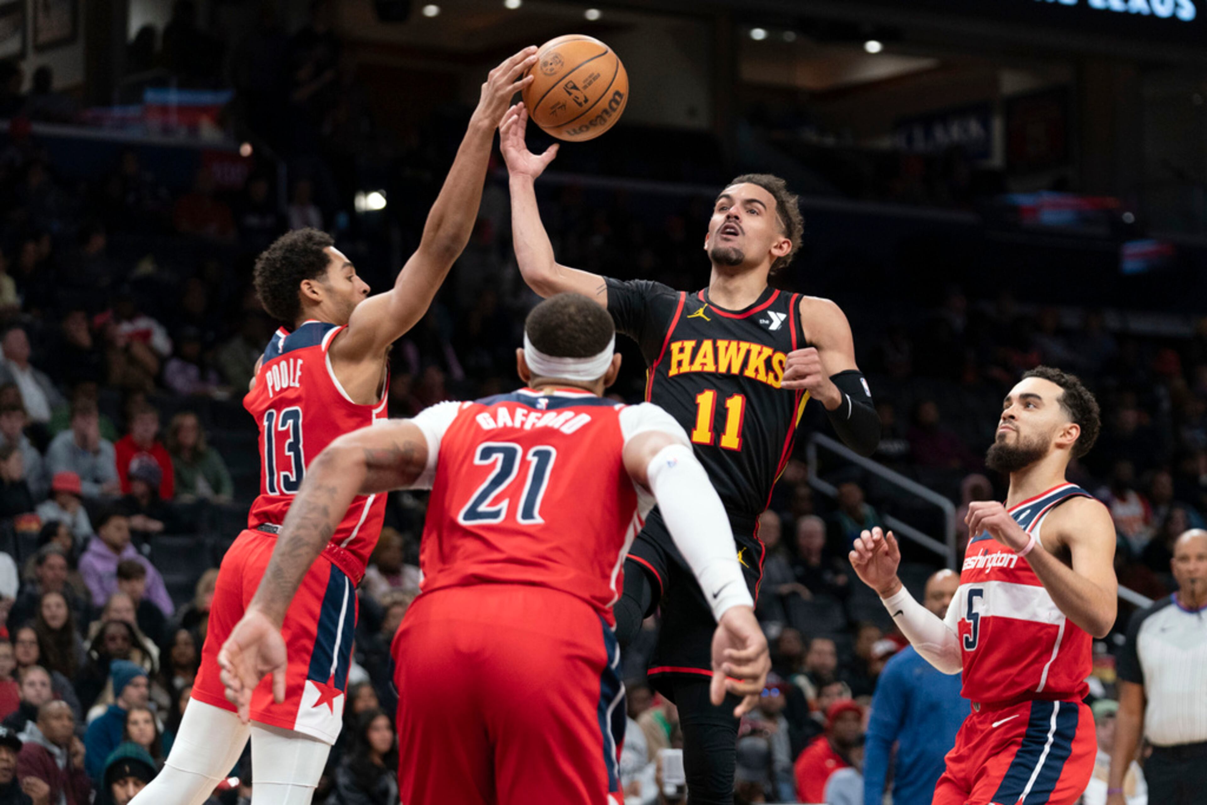 Atlanta Hawks' Trae Young (11) fights for the ball with Washington Wizards' Jordan Poole (13) during the second half of an NBA basketball game Sunday, Dec. 31, 2023, in Washington. (AP Photo/Jose Luis Magana)