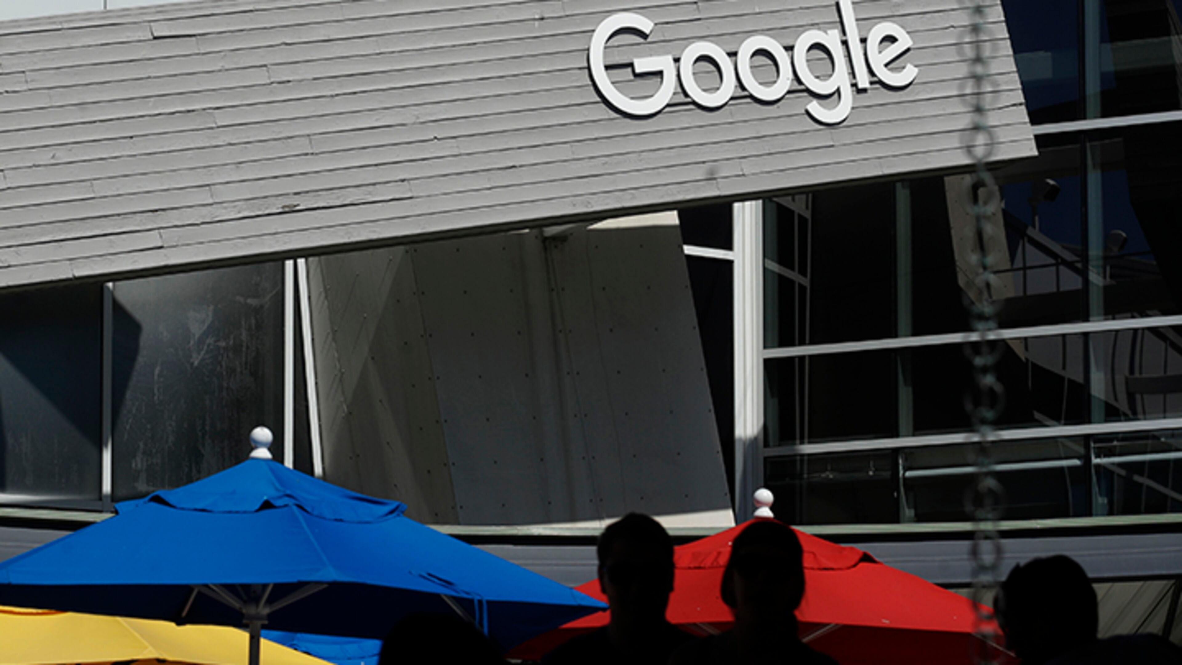 People walk by a Google sign on the campus in Mountain View, California. Google co-founders Larry Page and Sergey Brin are relinquishing control of parent company Alphabet to current Google CEO Sundar Pichai.