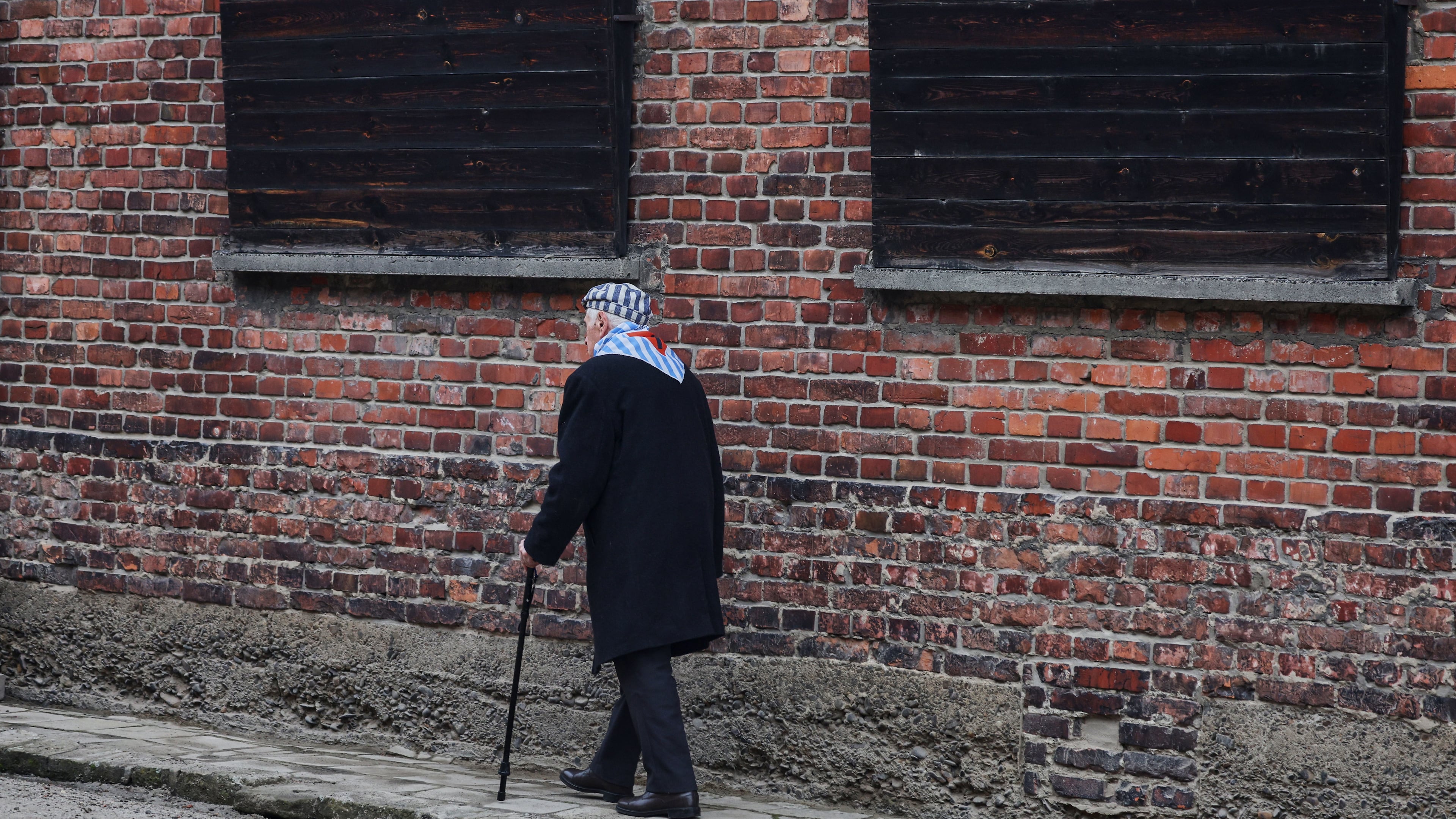 Holocaust survivor Stanislaw Zalewski walks along a wall in the Auschwitz Nazi death camp museum during a ceremony marking the 81th anniversary of the camp's liberation in Oswiecim, Poland, Tuesday, Jan. 27, 2026. (AP Photo/Beata Zawrzel)
