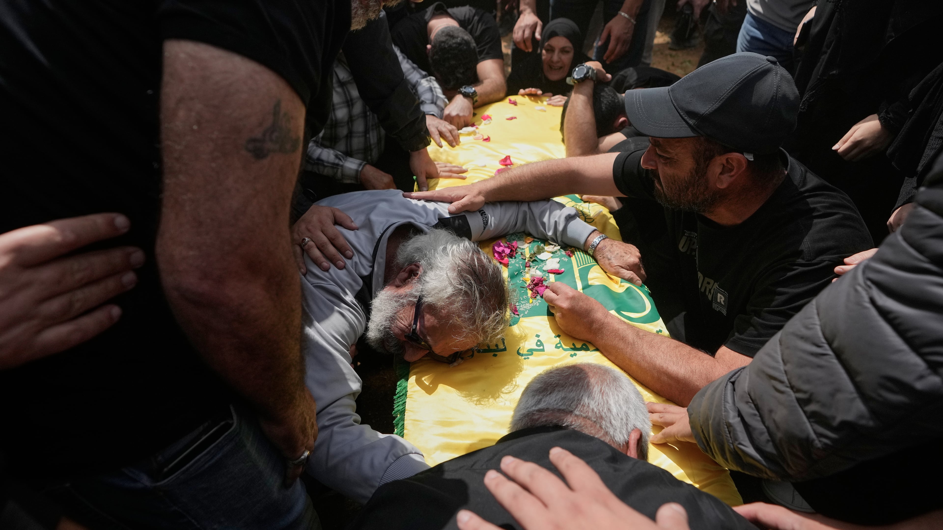 A man mourns over the coffin of a Hezbollah fighter who was killed in the war between Hezbollah and Israel during a mass funeral in Bazouriyeh village, south Lebanon, Monday, April 20, 2026. (AP Photo/Mohammed Zaatari)