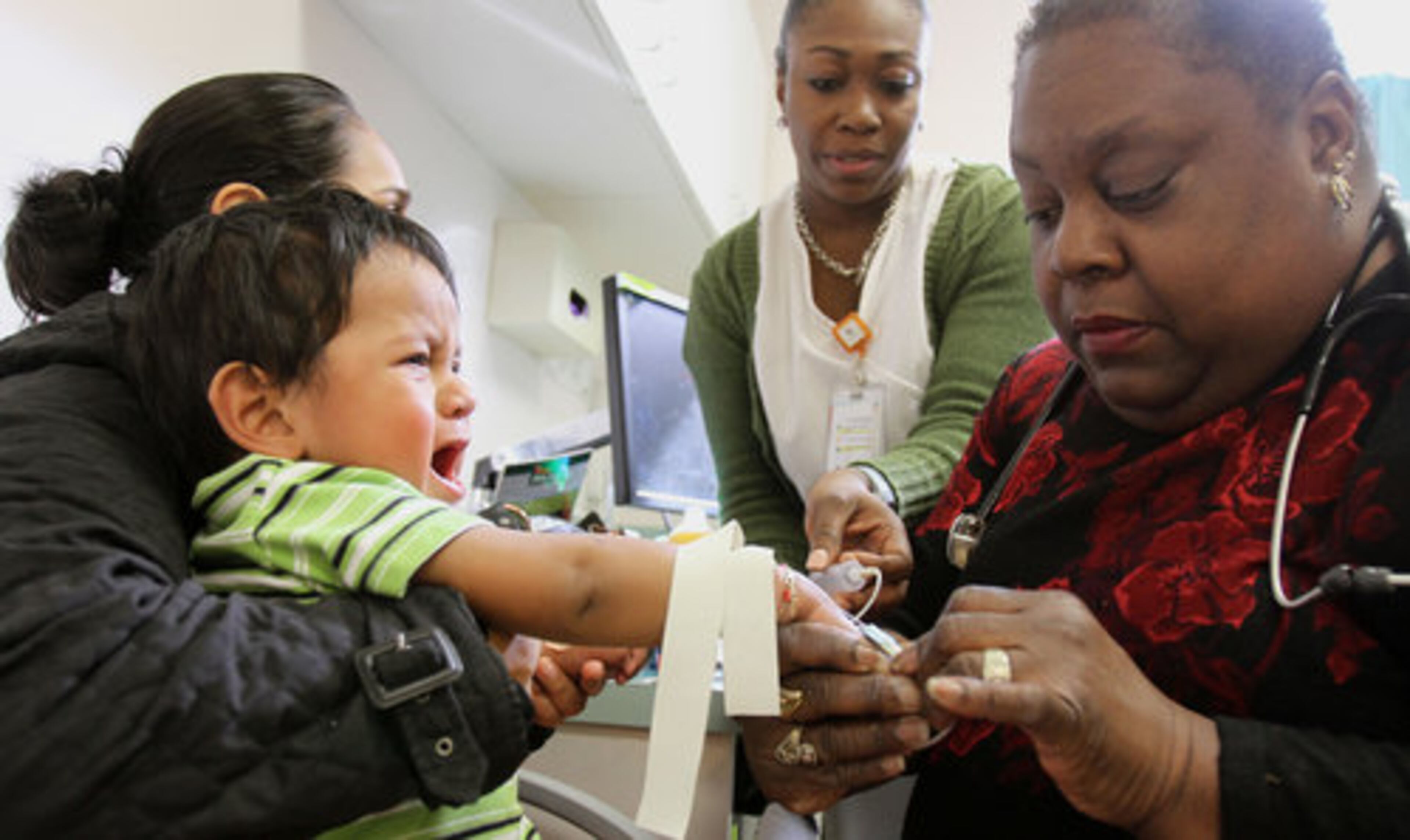 Otis W. Smith Health Center is one of two neighborhood clinics that Grady Memorial Hospital plans to close as a cost-saving measure. Here, Dr. Melba Johnson carefully draws blood from Rafayla Valente's two-year-old son, Sunny Garcia, with help from nurse practitioner Camille Bentuck at the clinic.