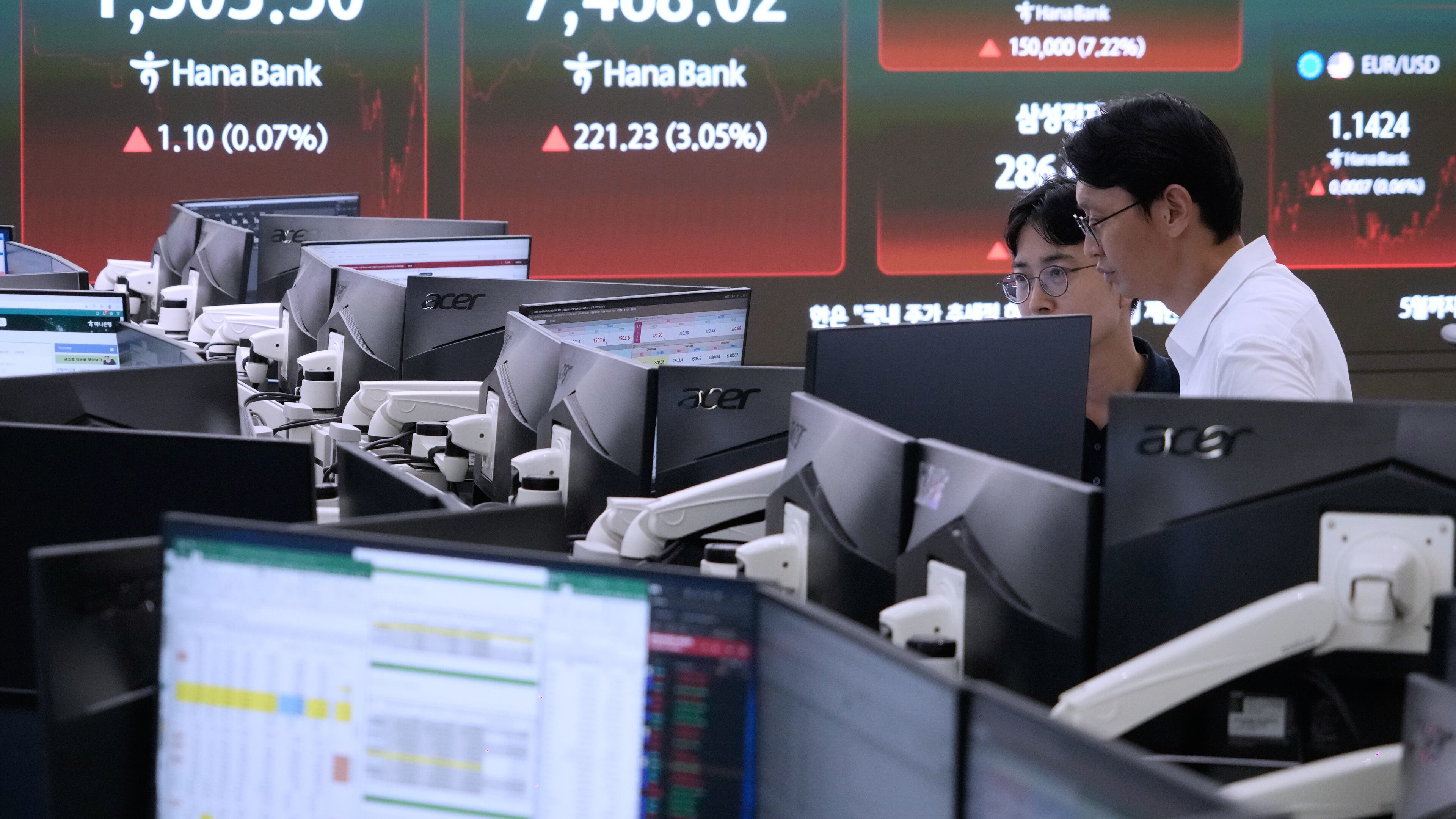 Currency traders watch monitors near a screen showing the Korea Composite Stock Price Index (KOSPI) and the foreign exchange rate between U.S. dollar and South Korean won at the foreign exchange dealing room of the Hana Bank headquarters in Seoul, South Korea, Thursday, July 9, 2026. (AP Photo/Ahn Young-joon)