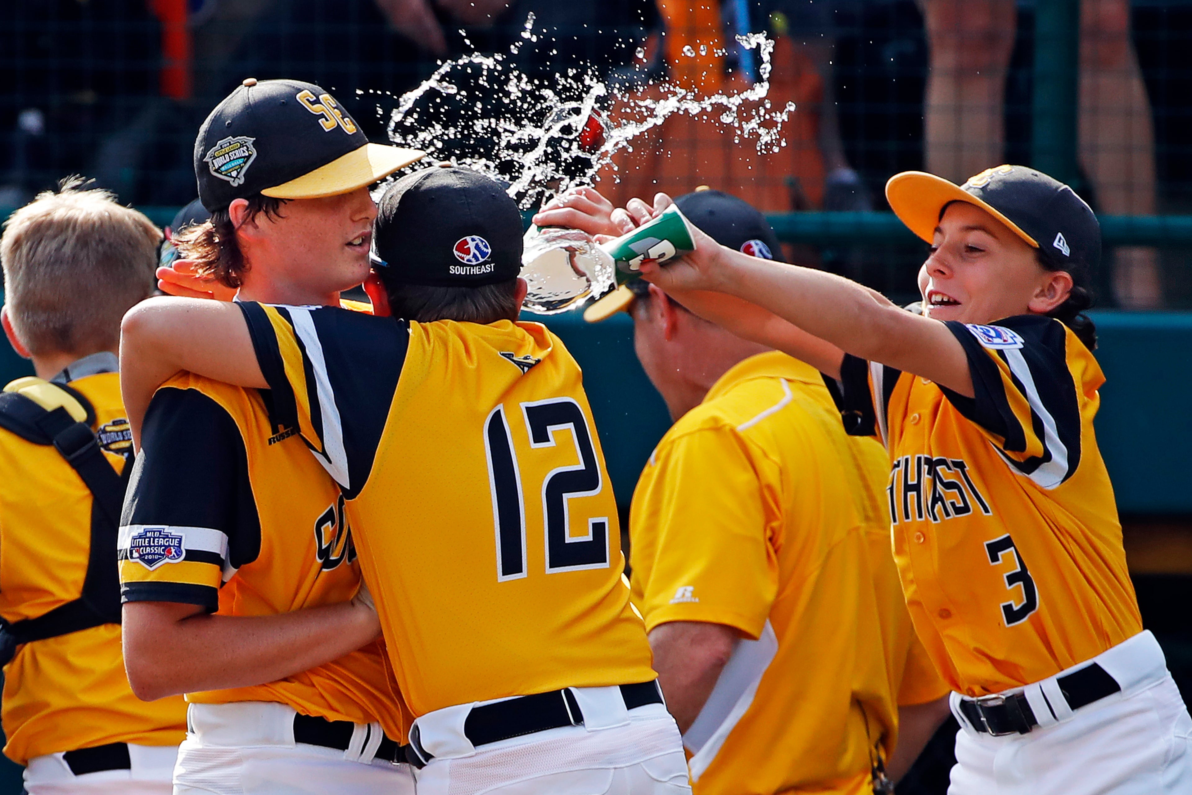 Peachtree City, Georgia pitcher Jansen Kenty left, gets a shower from Will Clem (3) as he is hugged by James Hopper (12) after getting a 4-3 complete-game win over Grosse Pointe Woods, Michigan in an elimination baseball game in United States pool play at the Little League World Series tournament in South Williamsport, Pa., Wednesday, Aug. 22, 2018. Georgia's win eliminates Michigan. (AP Photo/Gene J. Puskar)