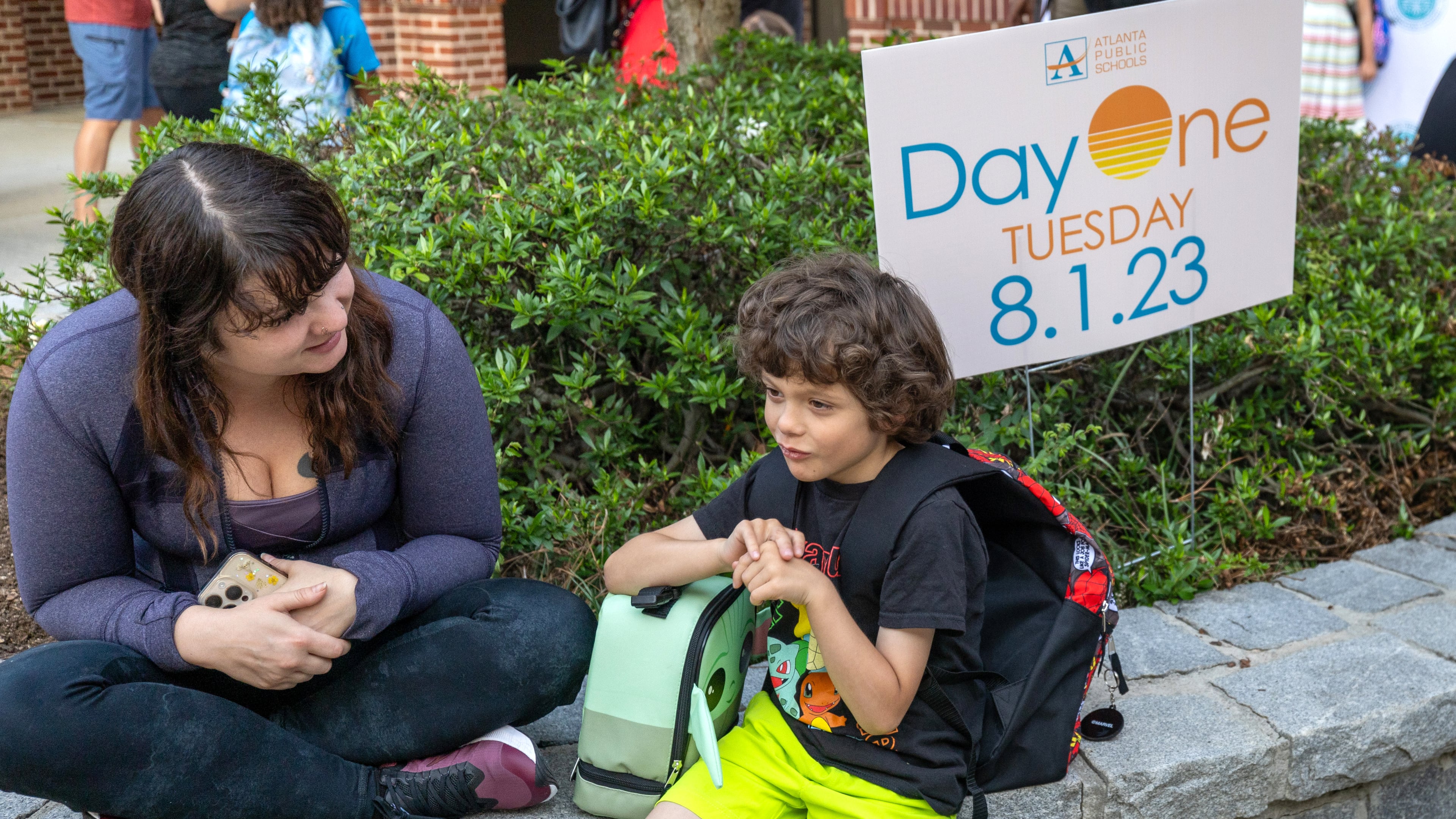 Ashley Simpson and her son Harrison, 7, sit outside Virginia-Highland Elementary, waiting for the first day of school to start Tuesday, Aug. 1, 2023. (Steve Schaefer/steve.schaefer@ajc.com)