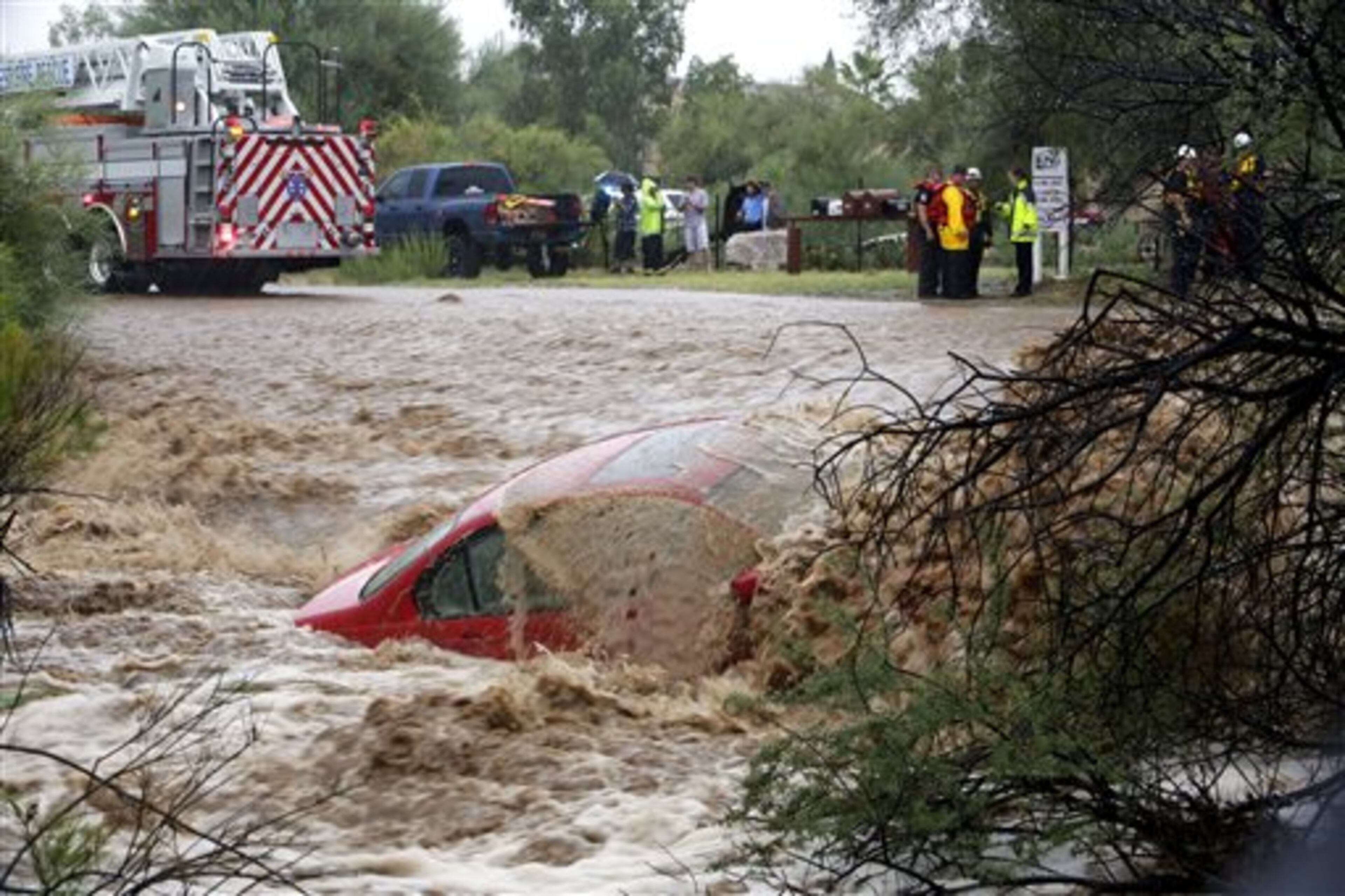 Water washes over the car after the driver was rescued by members of Northwest Fire District north of Tucson, Ariz., on Monday, Sept. 8, 2014. The Phoenix and Tucson metro areas were hit by heavy rains, causing flooding and damage. More than 3 inches of rain closed parts of several Phoenix freeways. In Tucson, the National Weather Service recorded nearly 2 inches of rain. (AP Photo/Arizona Daily Star, Ron Medvescek)