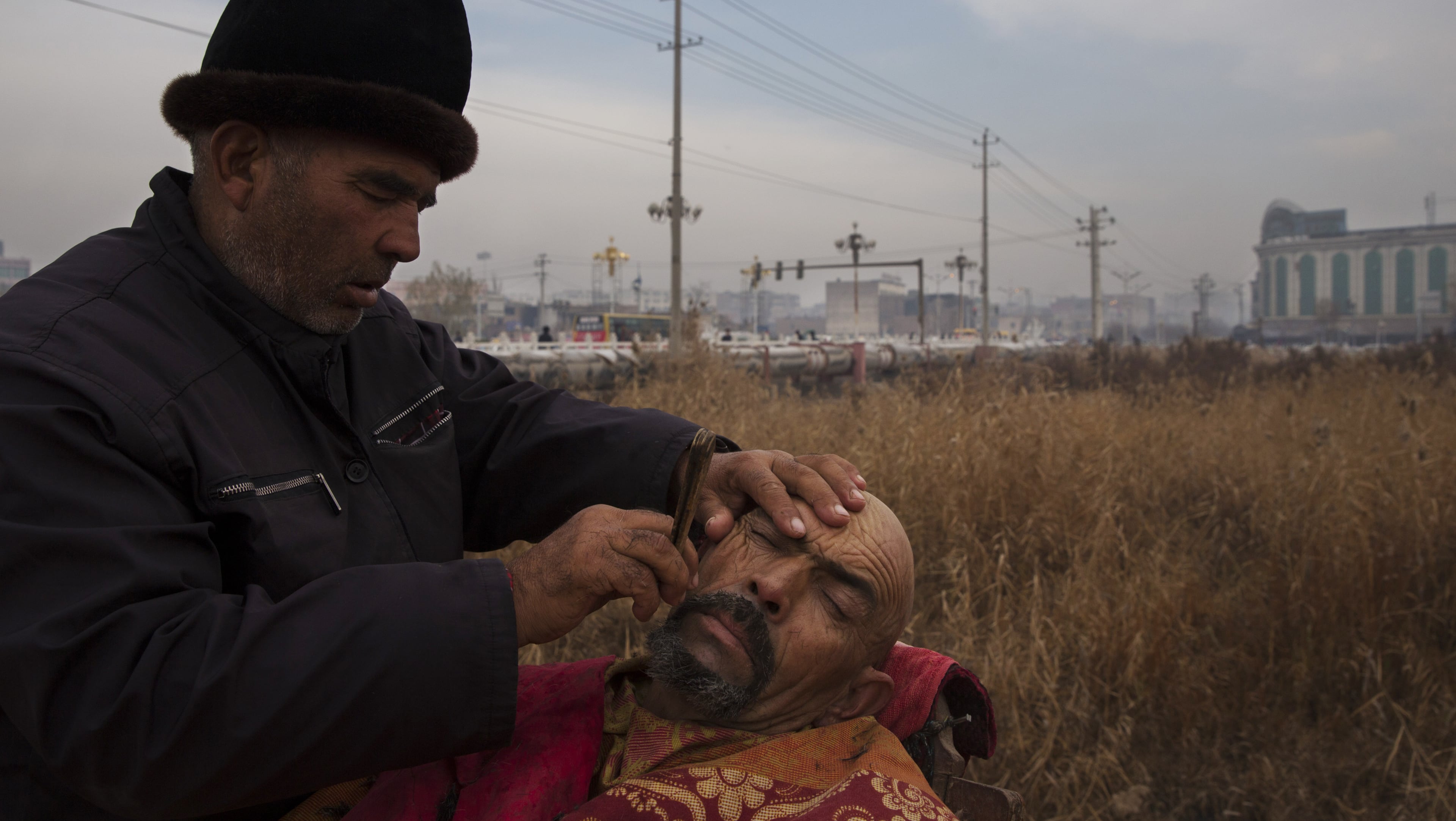 A barber gives an Uighur man a shave in Kashgar, in China’s far western province of Xinjiang. (Adam Dean/The New York Times)