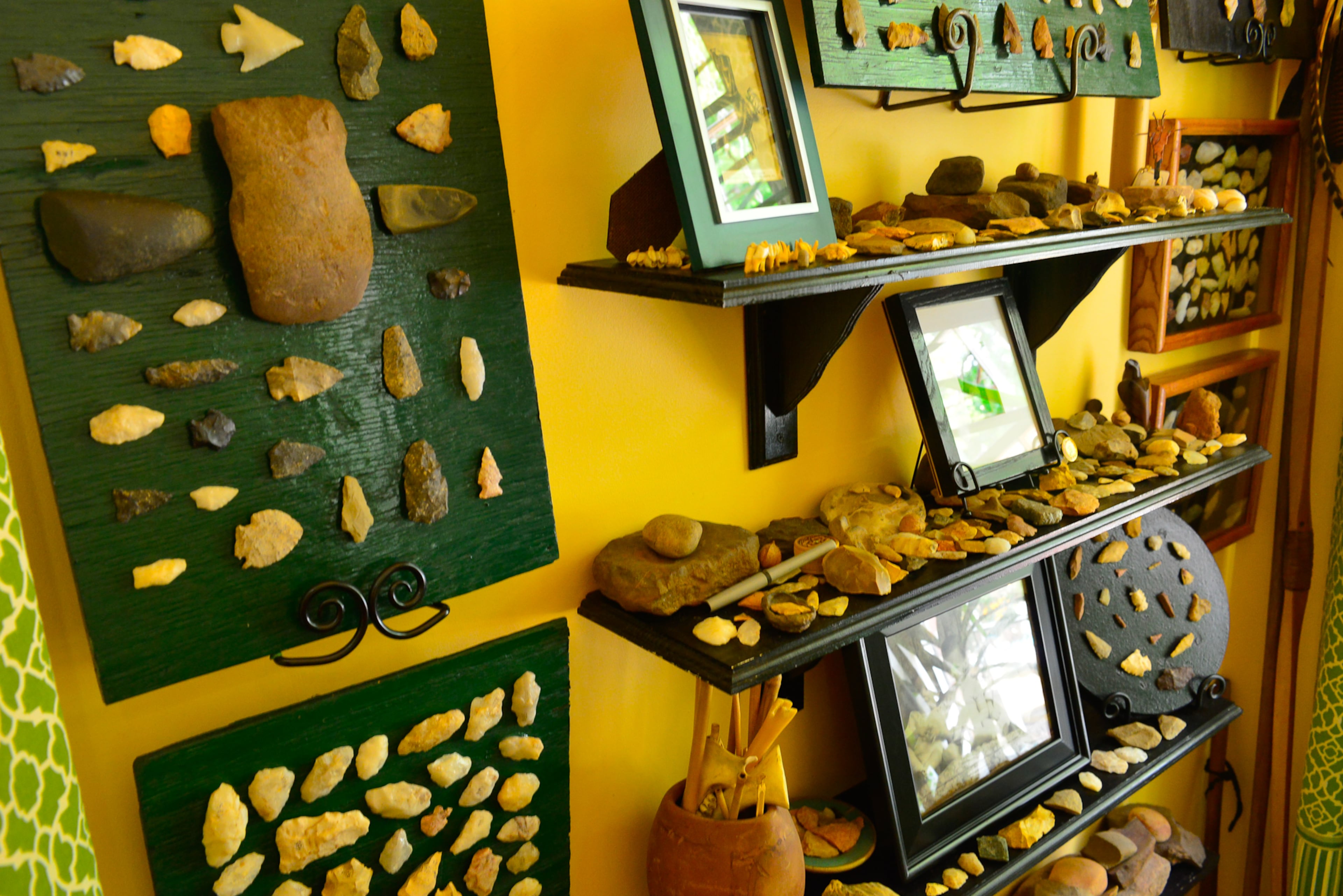 A collection of arrowheads and other artifacts found by homeowner Edward Storey fill shelves and part of a wall in the living room.