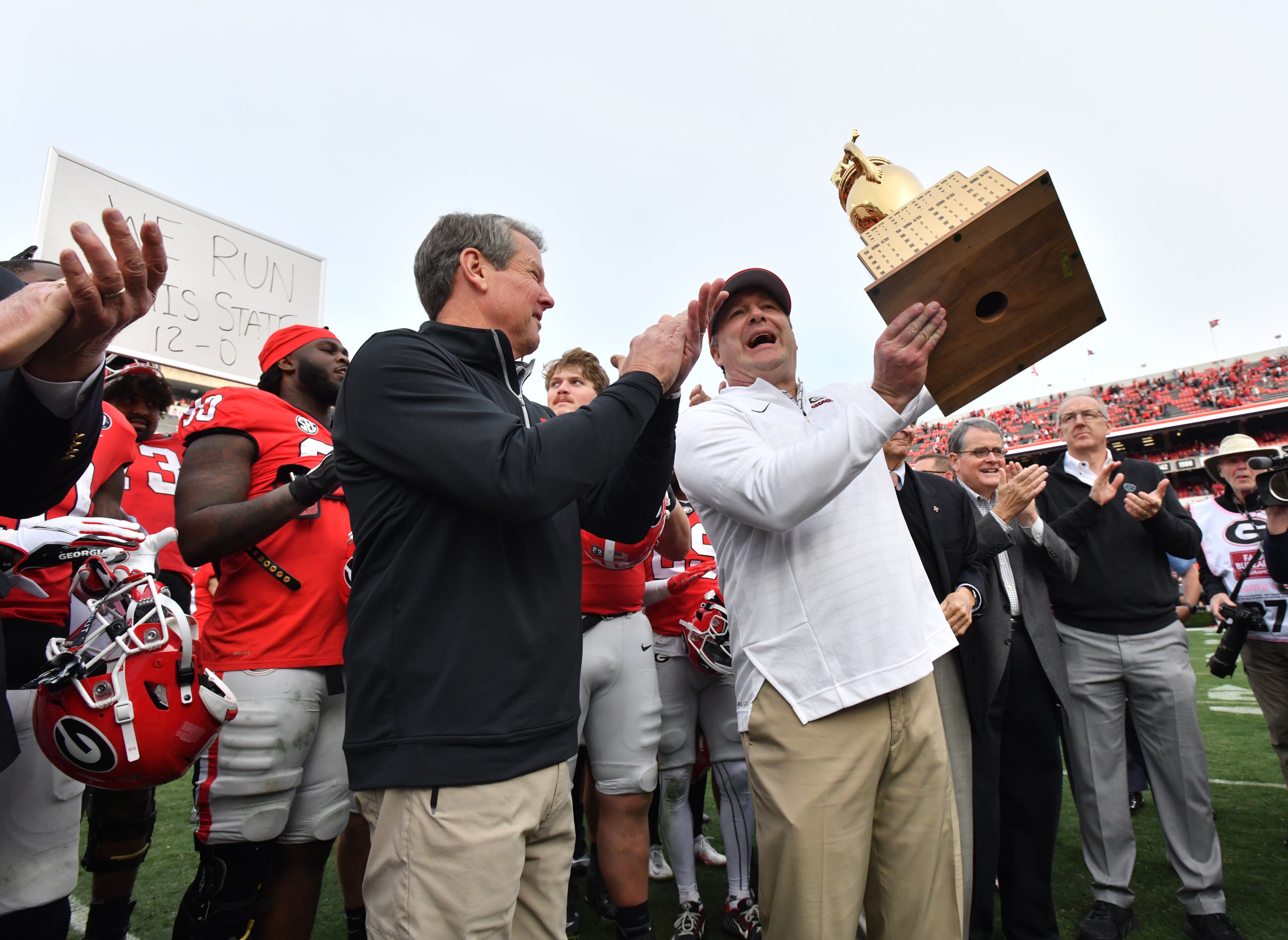 Georgia's head coach Kirby Smart holds up Governor’s Cup trophy as Governor Brian Kemp (left) looks after Georgia beat Georgia Tech. (Hyosub Shin / Hyosub.Shin@ajc.com)