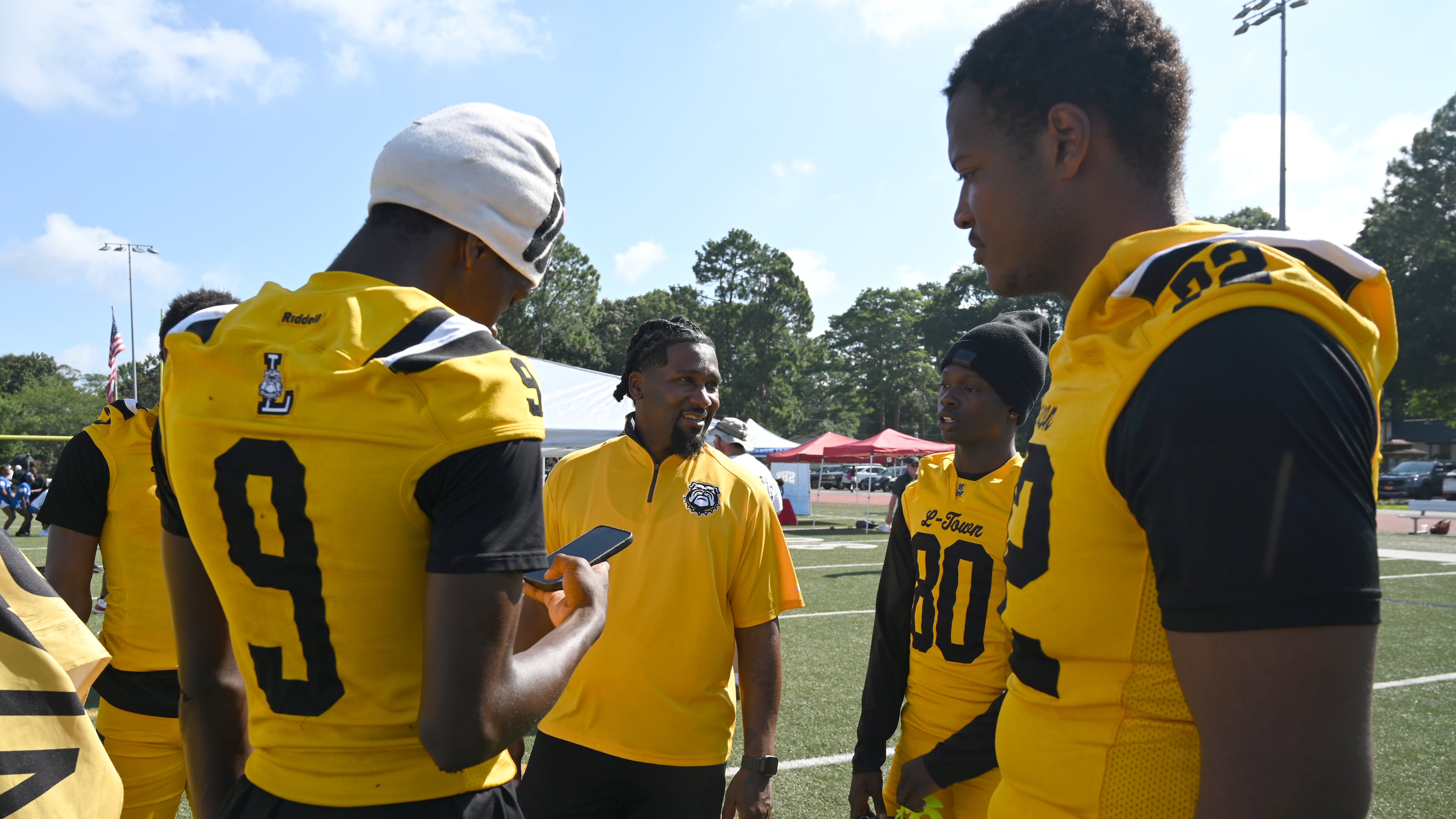 Lithonia football head coach Kevin Barnes (center) speaks to his players during the DeKalb County School District Athletics Media Day at Napoleon B. Cobb Stadium on Thursday, July 16, 2026, in Decatur. (Hyosub Shin/AJC)