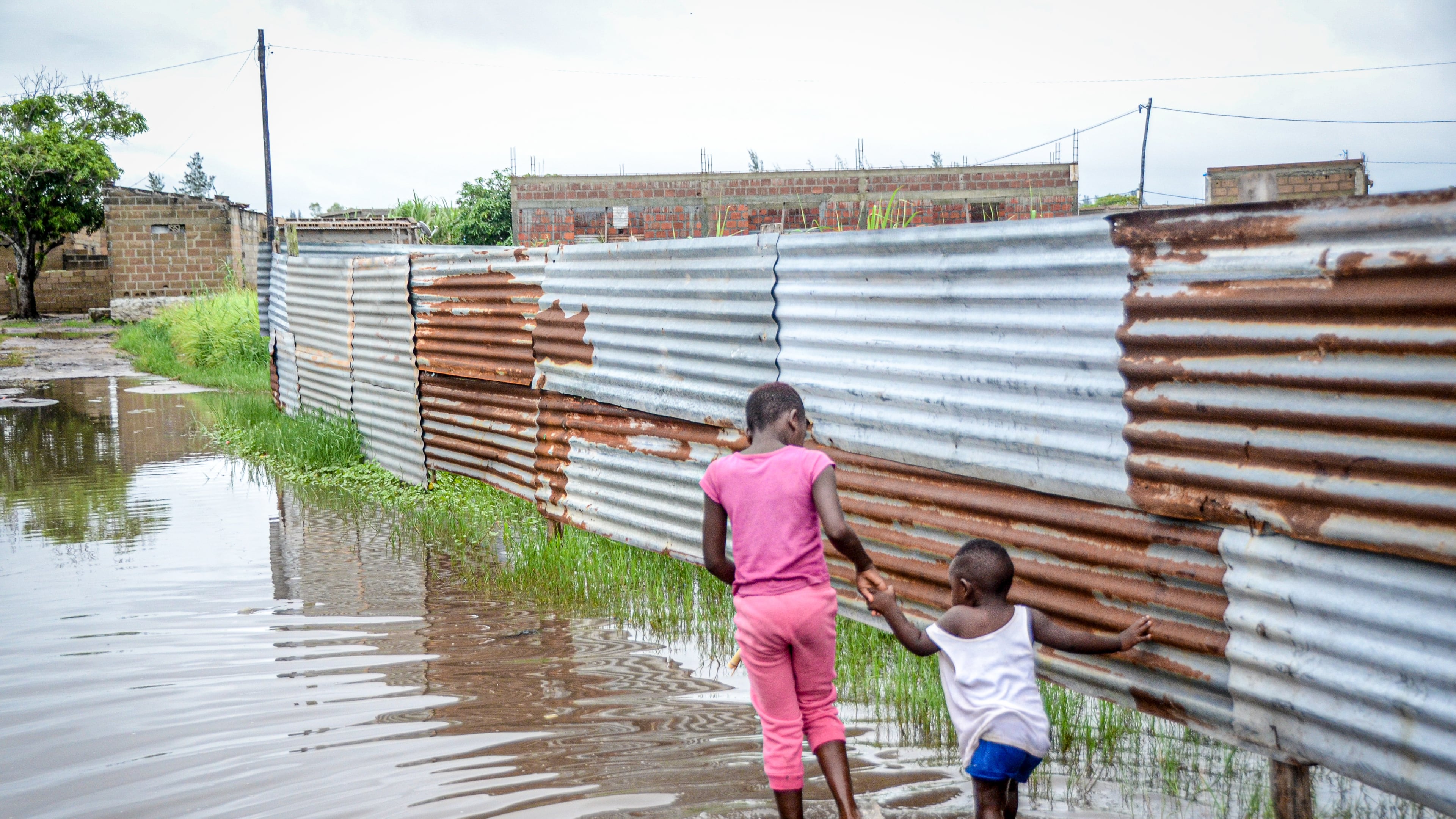 Children wade through floodwaters in a neighborhood in Maputo, Mozambique, on Friday, Jan. 16, 2026. (AP Photo/Carlos Uqueio)