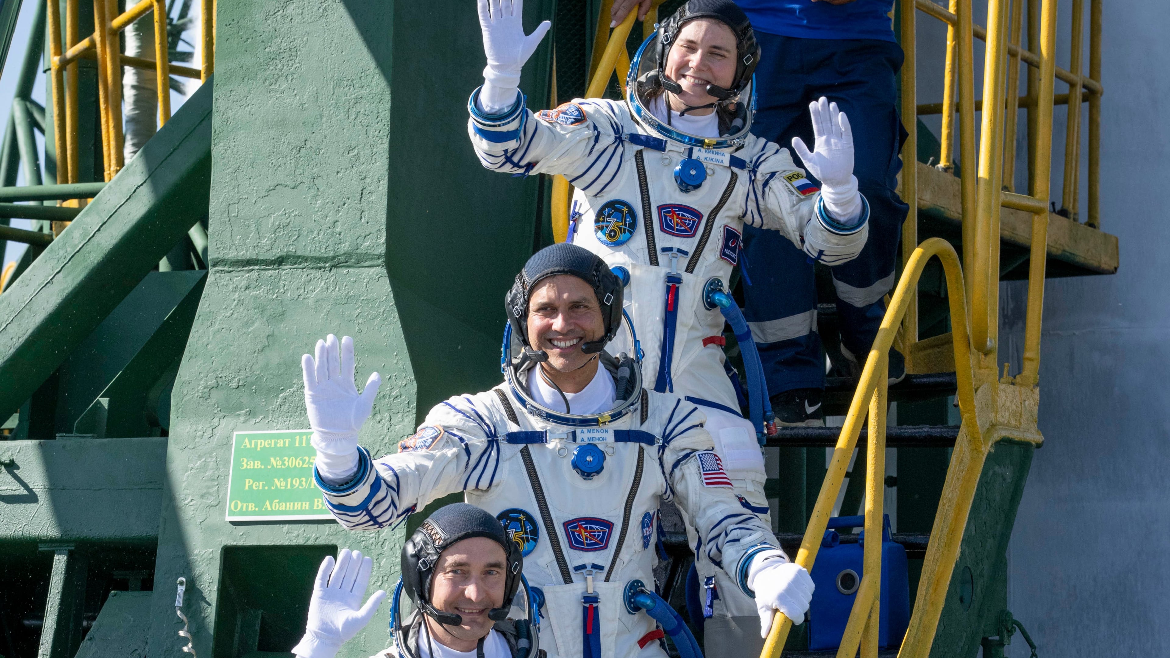 Expedition 75 Roscosmos cosmonaut Anna Kikina, top, NASA astronaut Anil Menon, middle, and Roscosmos cosmonaut Pyotr Dubrov, bottom, wave farewell prior to boarding the Soyuz MS-29 spacecraft for launch, Tuesday, July 14, 2026 at the Baikonur Cosmodrome in Kazakhstan. (Bill Ingalls/NASA via AP)