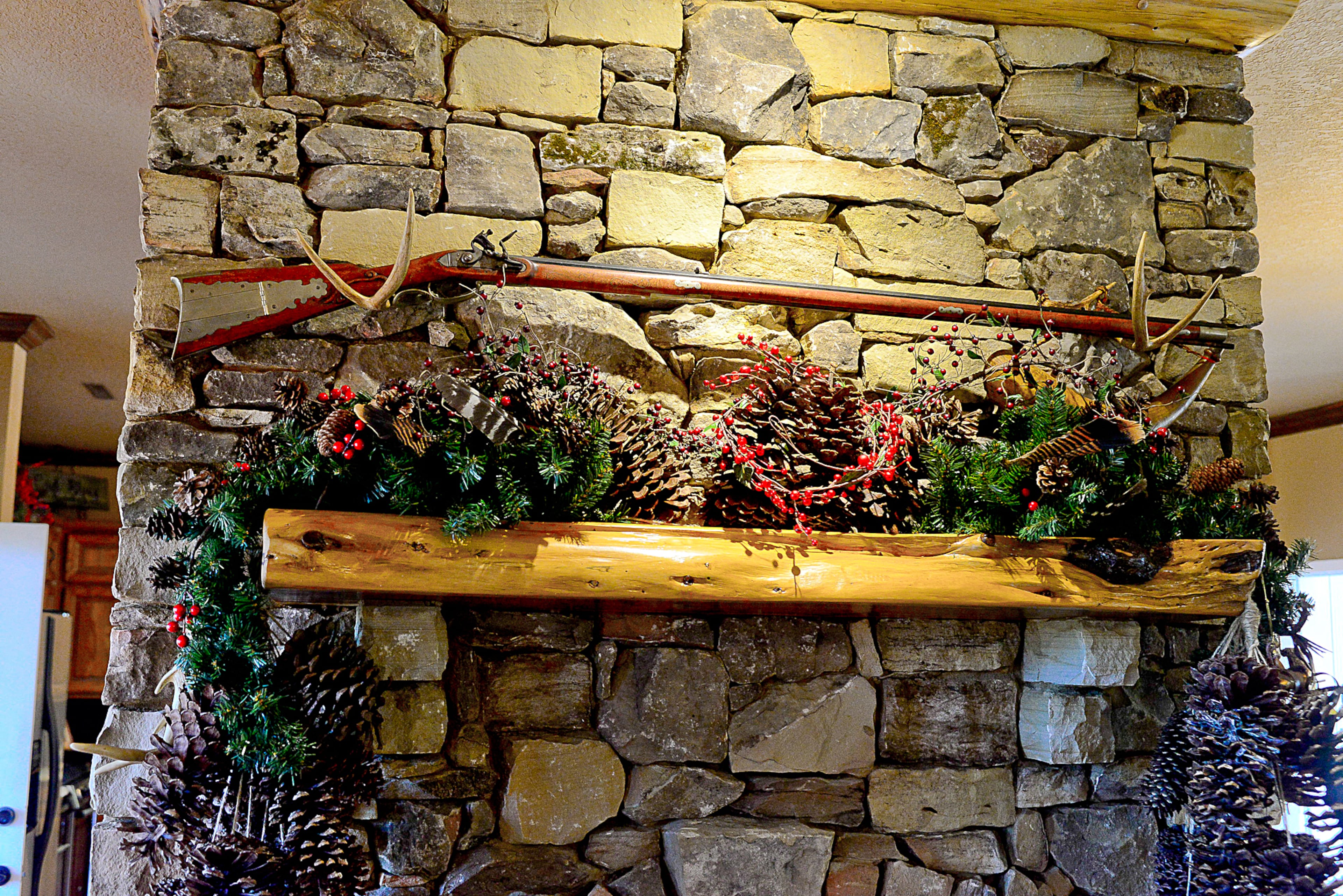 Homeowner Calvin Rolan built the Kentucky flintlock rifle, and his wife, Marcelle, fit in Christmas decorations using pine cones, deer antlers and burlap below it on the mantle.