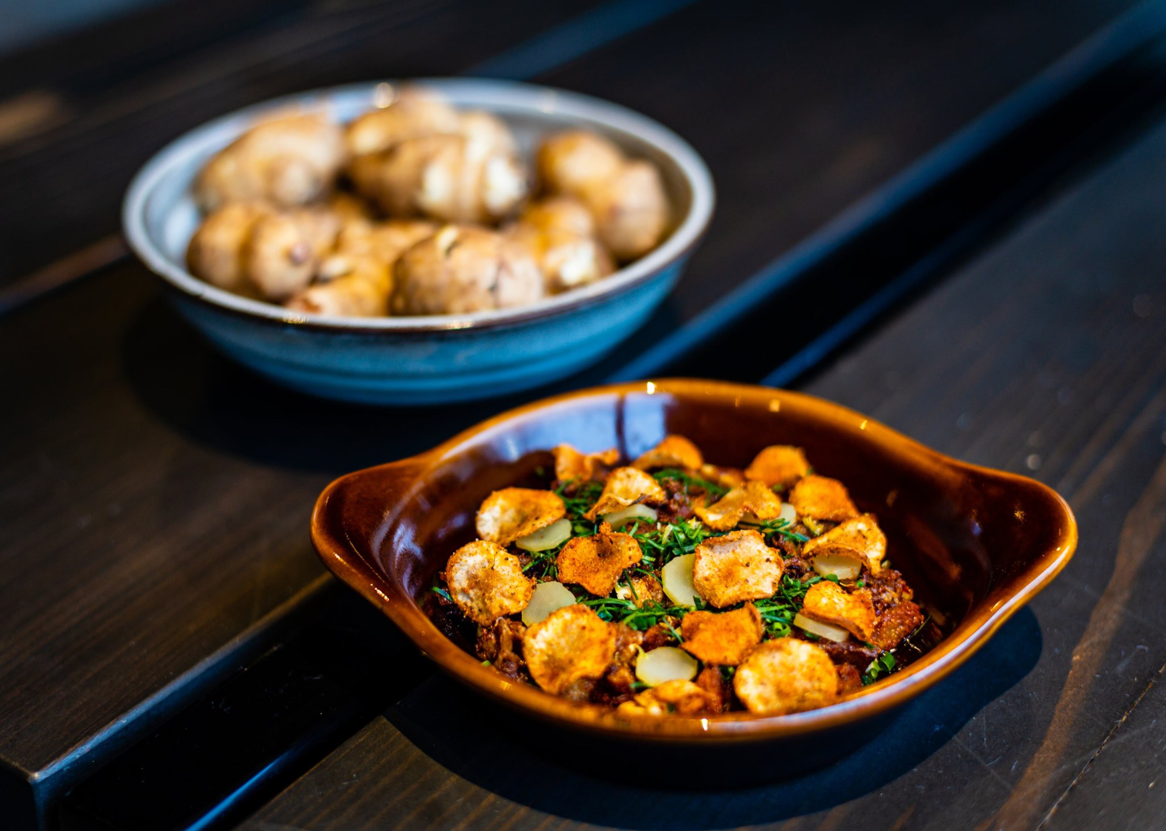A dish of deviled crab, sunchokes and preserved sunflower at Cold Beer, flanked by a bowl of raw sunchokes. CONTRIBUTED BY HENRI HOLLIS