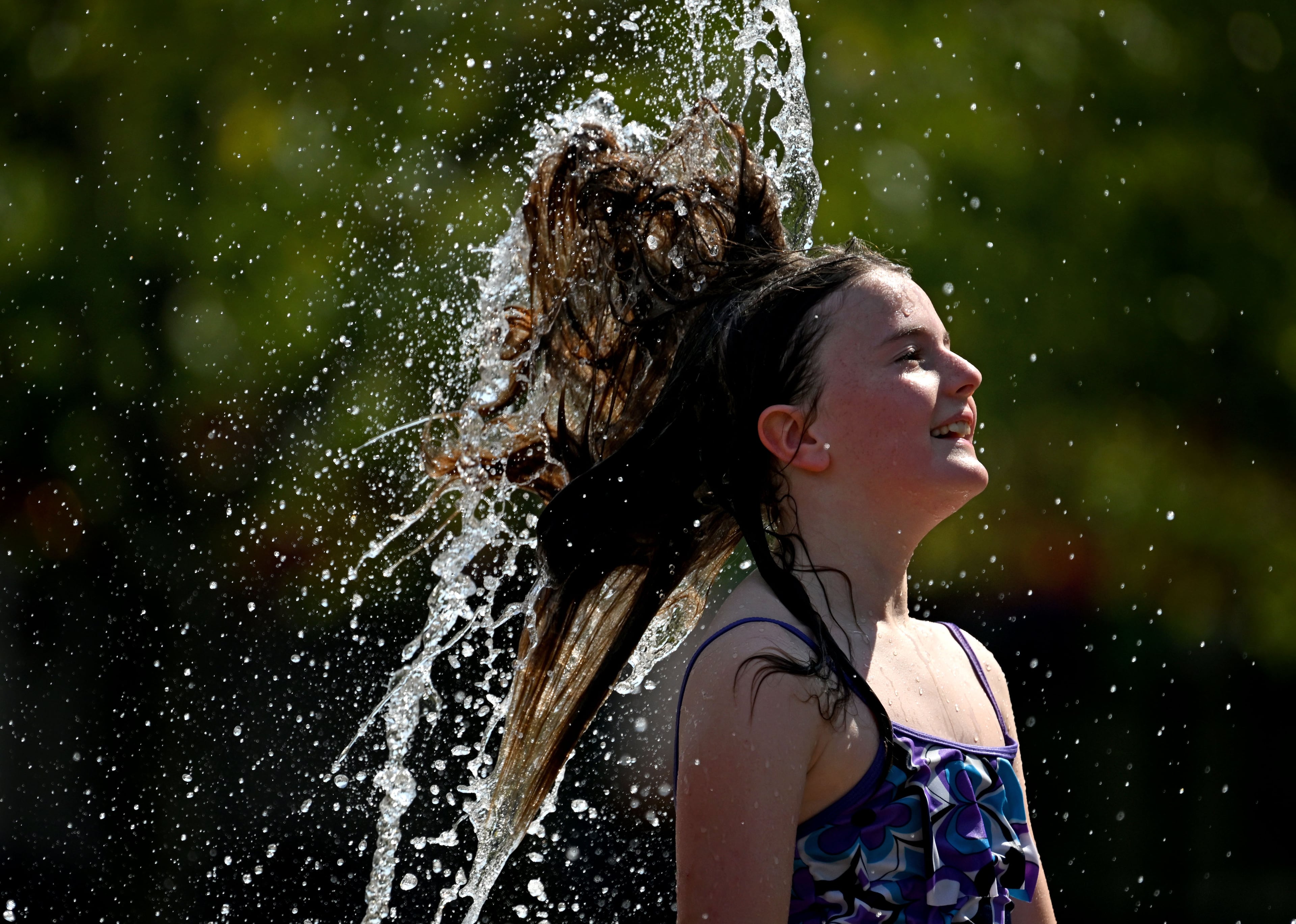 Kate Bayne, 10, plays in the Big Splash fountain at Town Center Park on Wednesday, Sept. 2, 2026, in Suwanee. The National Weather Service predicts hot and humid conditions to continue through a busy Labor Day weekend of college and high school football, events and activities in Atlanta and beyond. (Hyosub Shin/AJC)