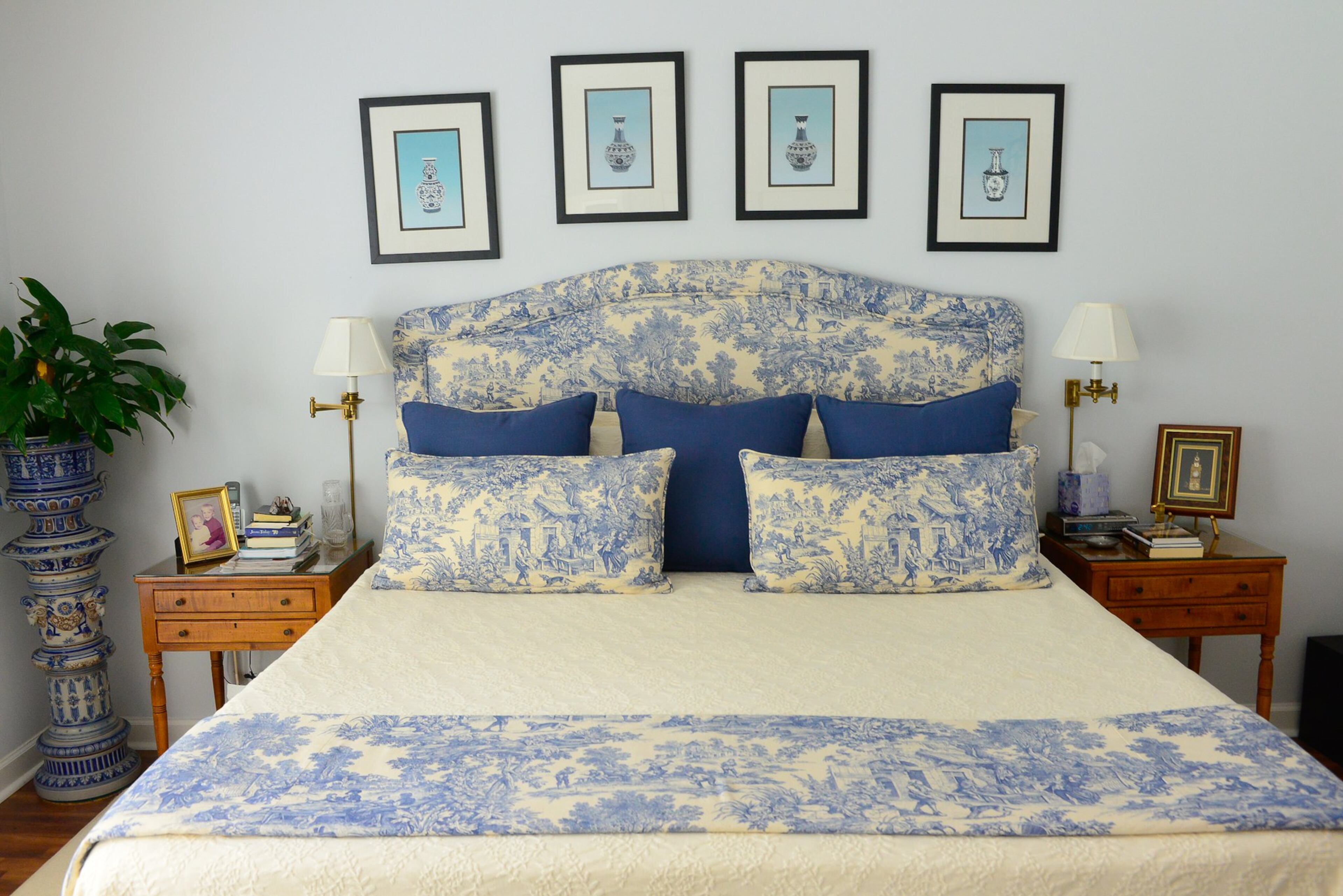 A blue and white pottery plant stand complements the traditional blue toile upholstered headboard and bedding in the master bedroom. The pale blue color scheme creates a relaxing retreat for Linda and Chris, and small silk pictures of Asian vases framed above their bed are everyday reminders of the couple's trip to China in 2007.