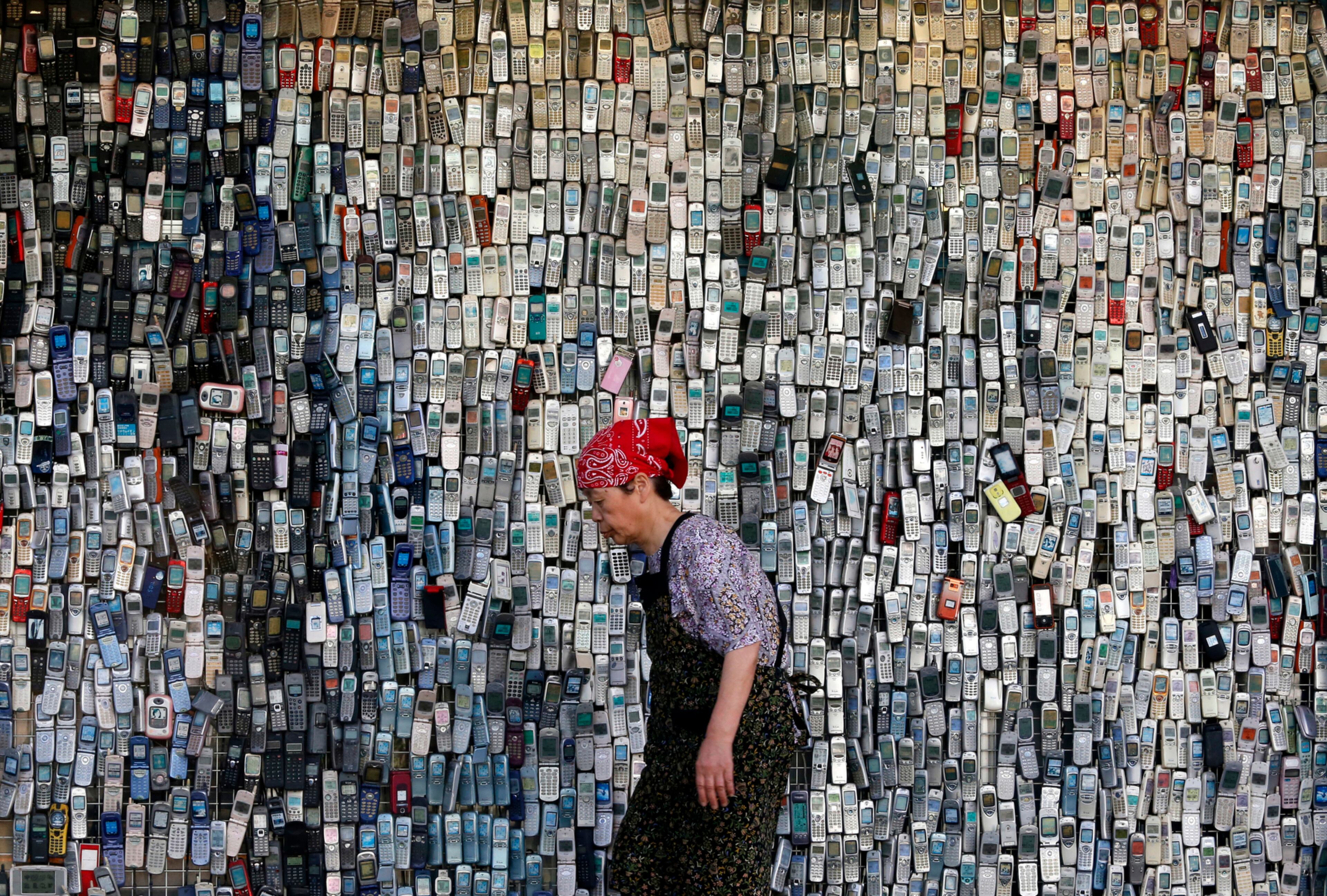 CAN YOU HEAR ME NOW--A woman walks past a wall of mock-up mobile phones displayed outside an electronics store in downtown Tokyo, Japan, Thursday, June 2, 2016. The store owner started this display with a few thousands of cellphones ten years ago, which continue to draw attention from those who pass by. (AP Photo/Shuji Kajiyama)