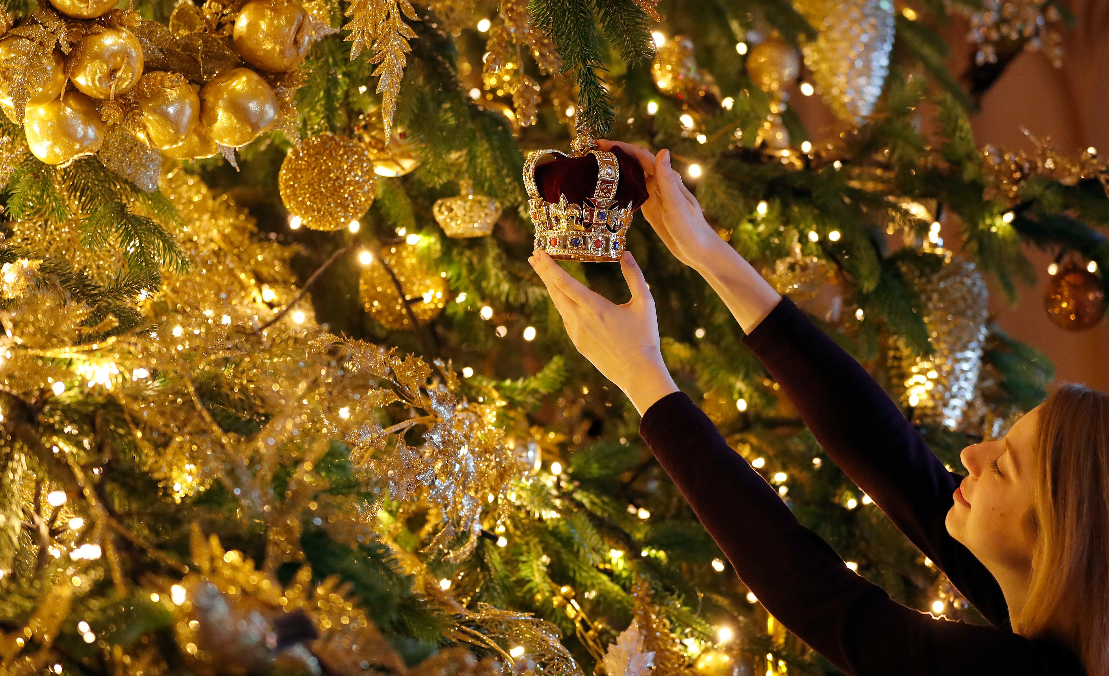 A 20ft Nordmann Fir tree from Windsor Great Park, entirely dressed in gold, is decorated and stands at the end of St George's Hall, at Windsor Castle in Windsor, England, Friday, Nov. 30, 2018. (AP Photo/Frank Augstein)