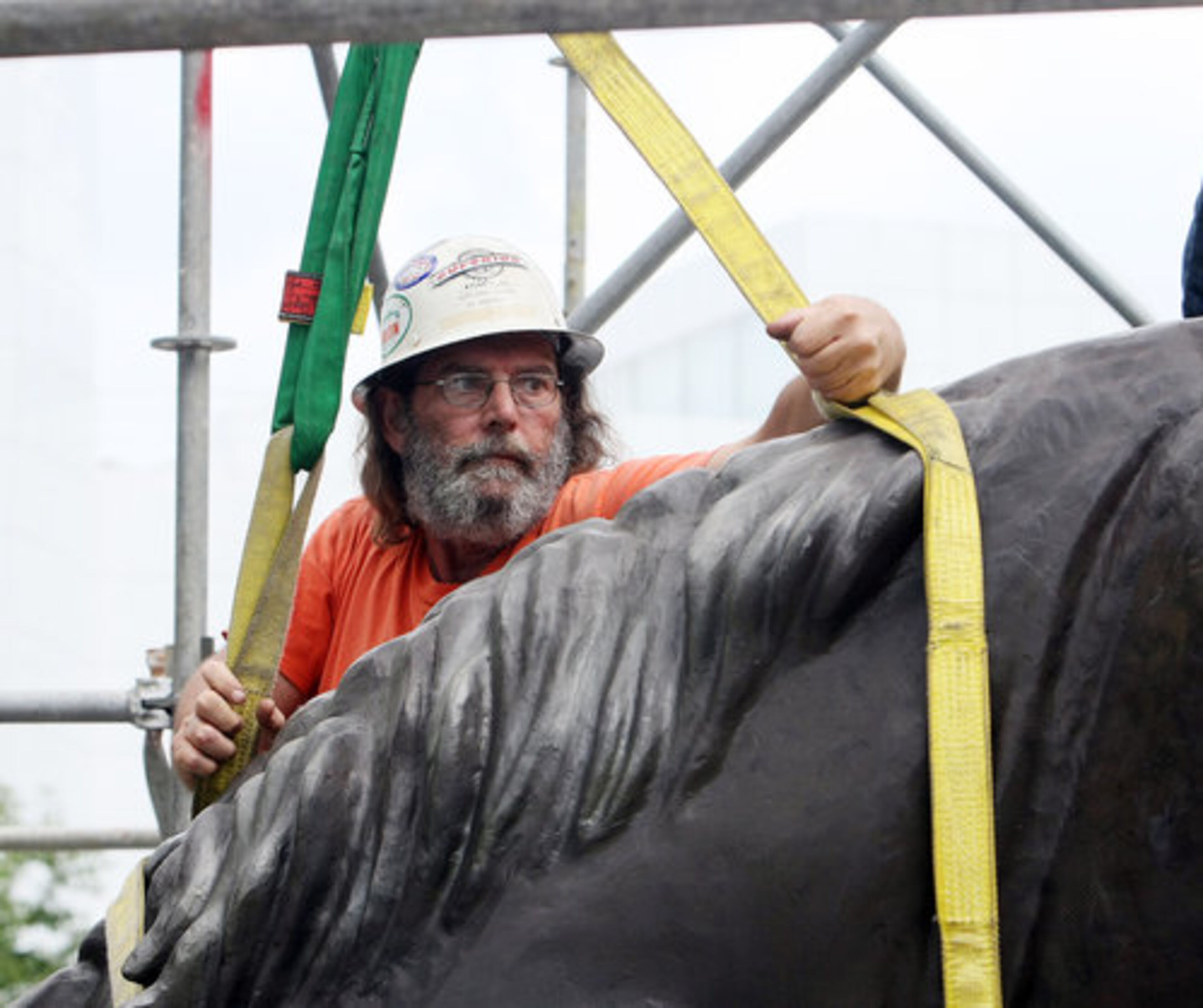 Ed Beard attaches a harness to the head of a three-story replica.