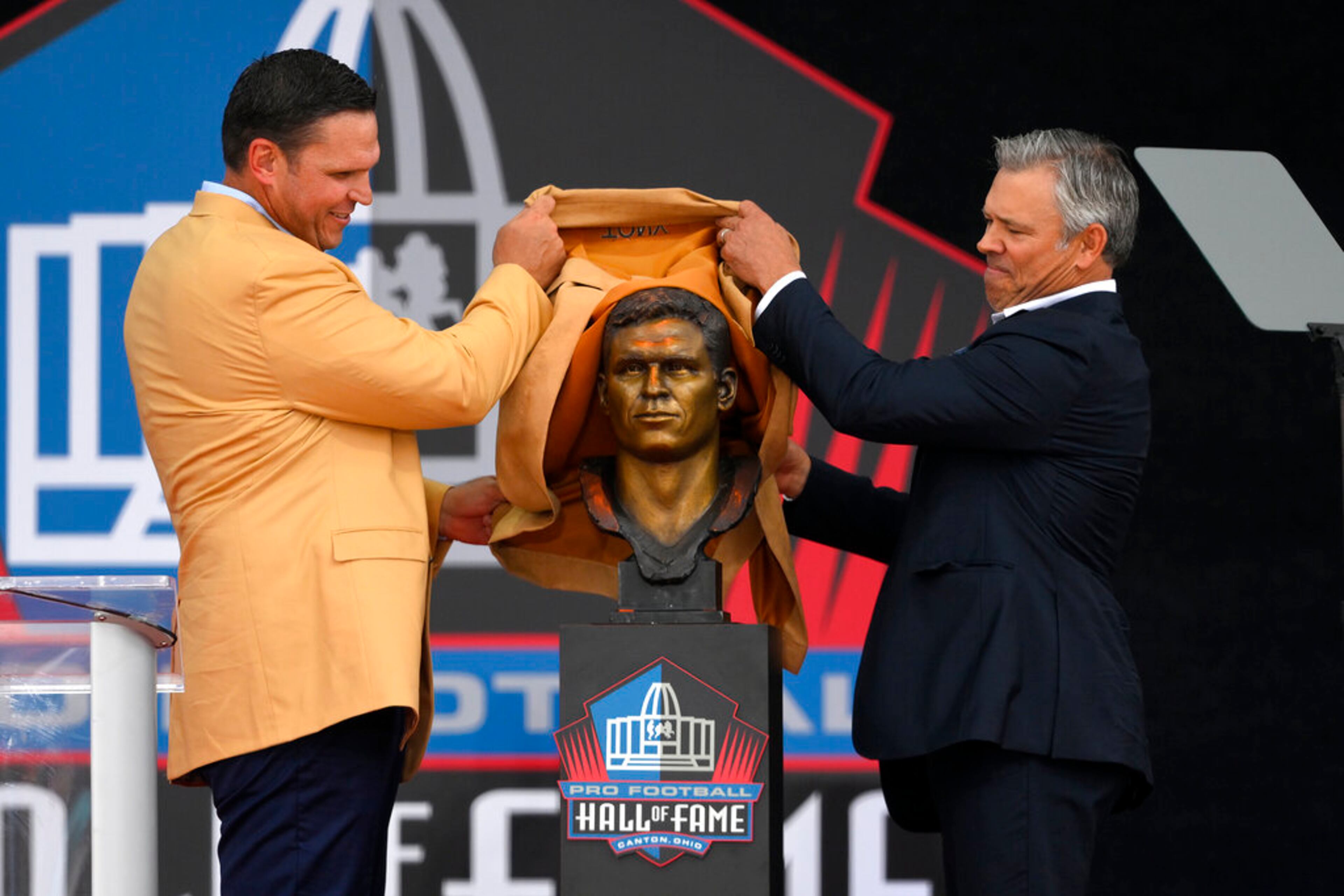 Former NFL player Tony Boselli, left, and his presenter Mar Brunell unveil his bust before speaking during his induction into the Pro Football Hall of Fame, Saturday, Aug. 6, 2022, in Canton, Ohio. (AP Photo/David Richard)