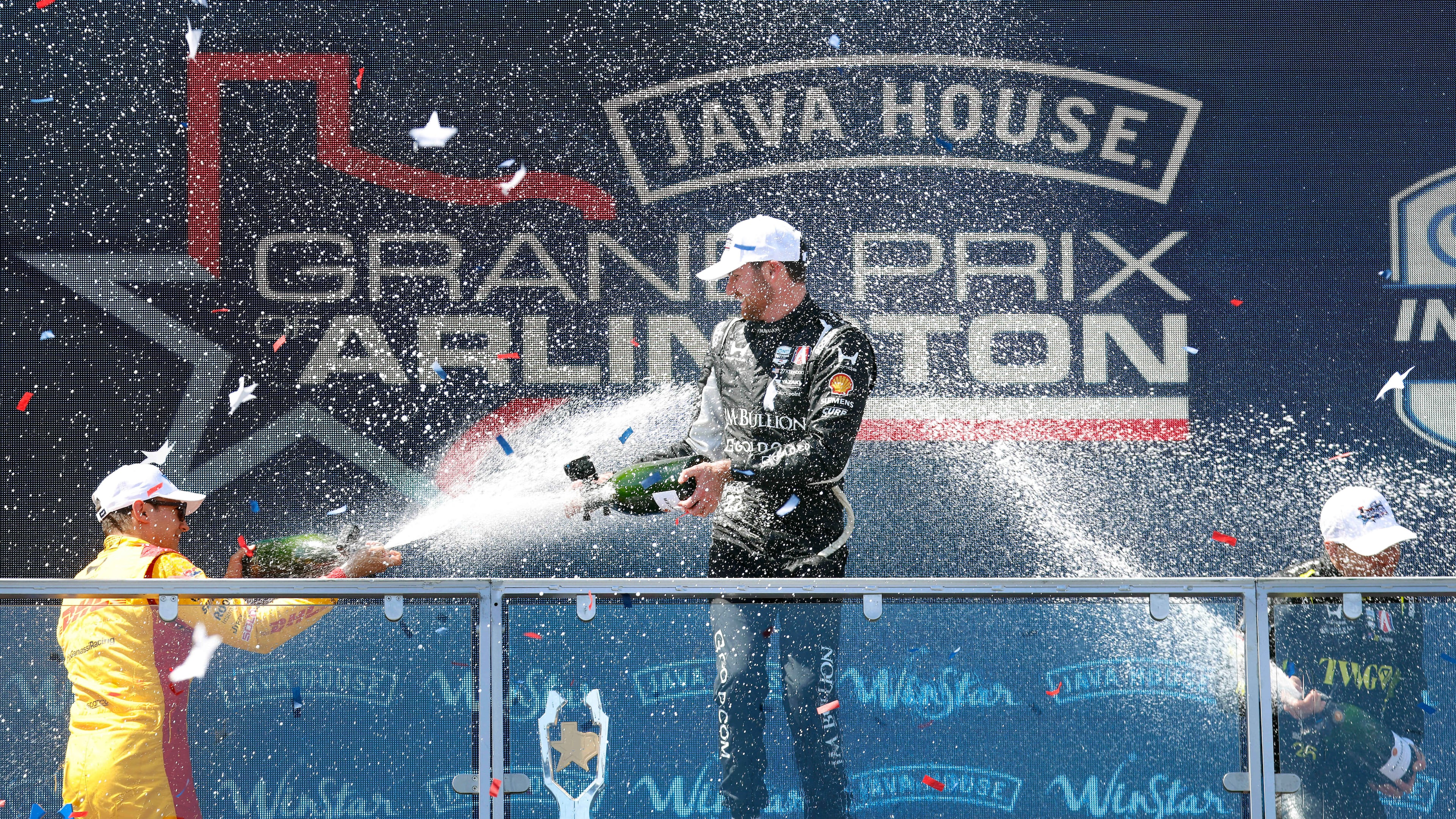 Grand Prix of Arlington winning driver Kyle Kirkwood of Andretti Global, center, is doused with champagne by second place finisher Alex Palou, left, and third place finisher Will Power following at the Grand Prix of Arlington auto race, Sunday, March 15, 2026, in Arlington, Texas. (Tom Fox/The Dallas Morning News via AP)