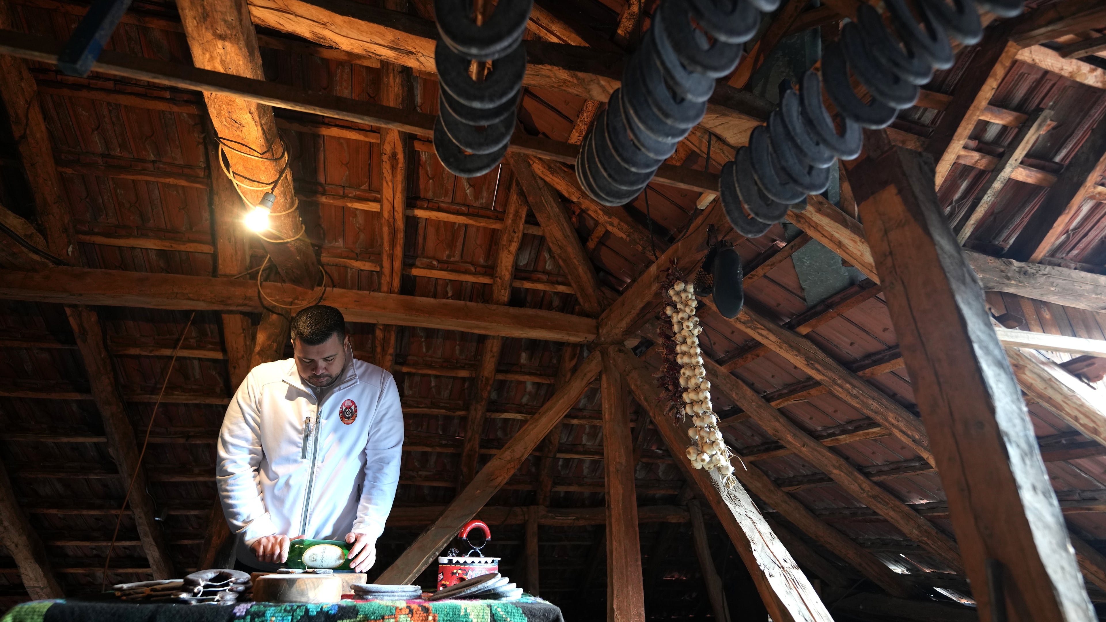 Misa Rajic irons sausage using a glass bottle in the attic of his home in Pirot, Serbia, on Feb. 13, 2026. (AP Photo/Darko Vojinovic)