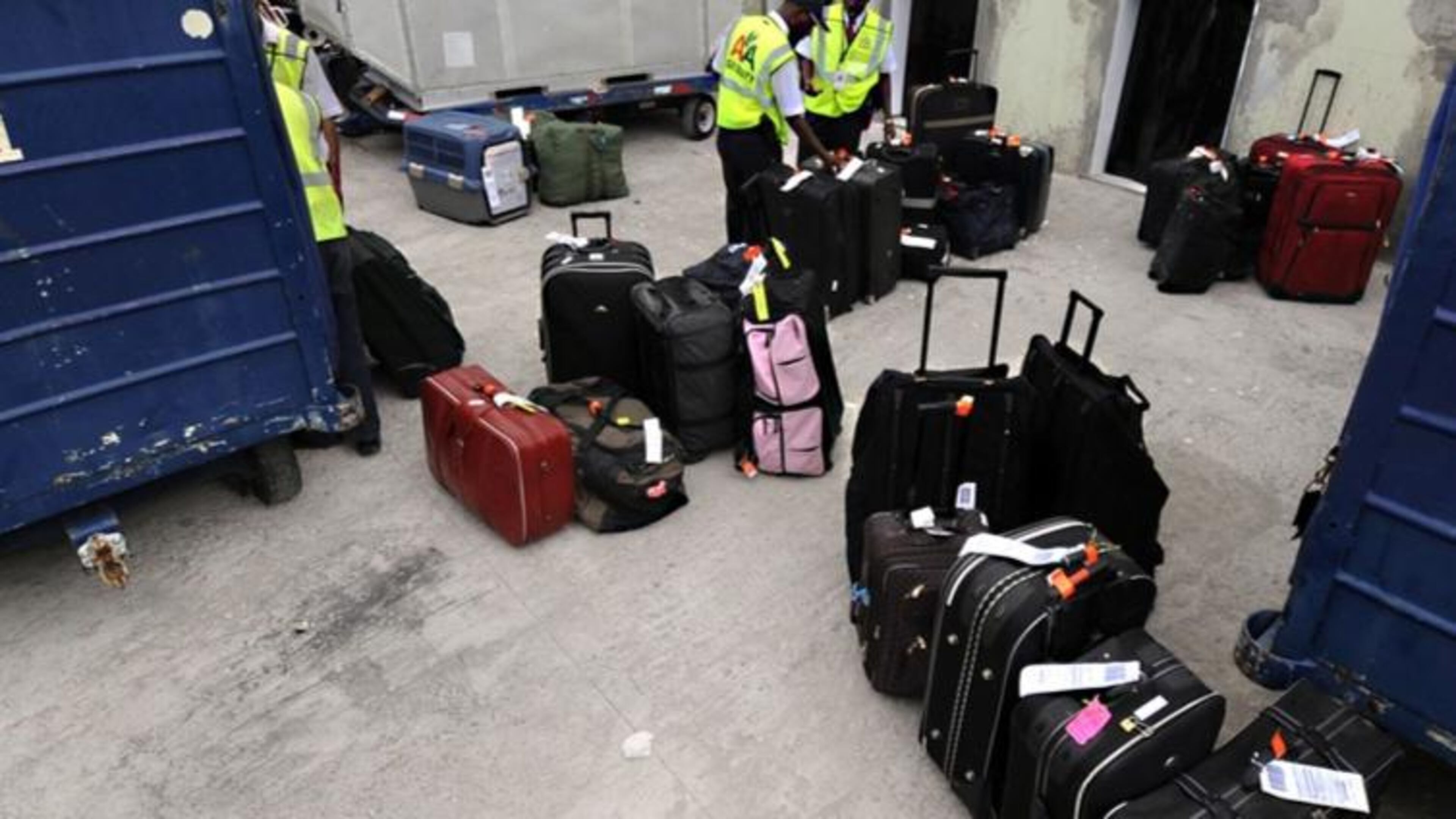Airport workers handle luggage.