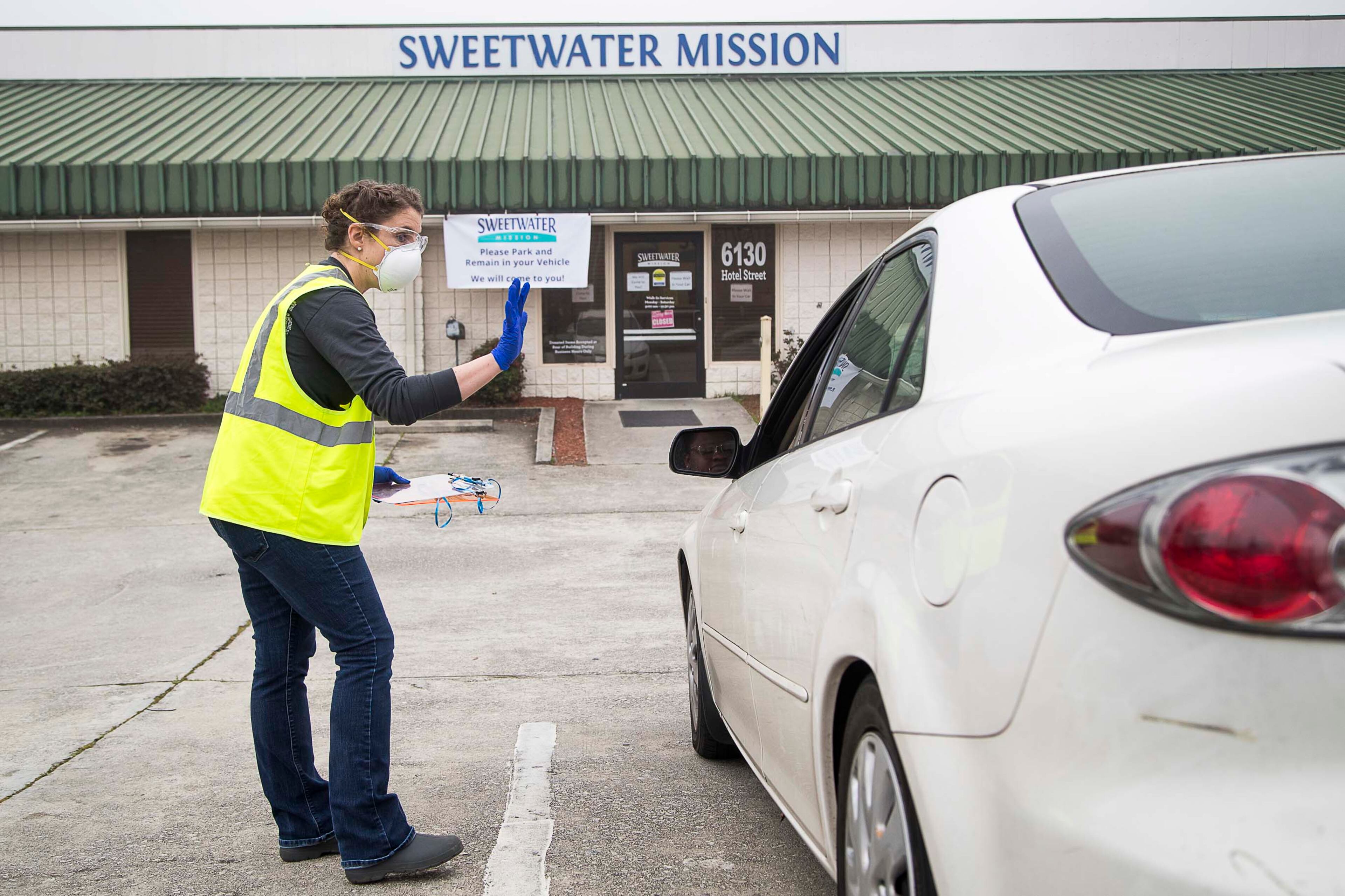 03/19/2020 -- Austell, Georgia -- Sweetwater Mission Clothing Program Coordinator, Mary Beth Alexander receives a patron's information during the food distribution "drive-thru" at Sweetwater Mission in Austell, Thursday, March, 19, 2020. Alexander, along with other volunteers and employees, wore protective wear while facilitating the food distribution. Normally patrons are allowed inside the facility to pick their food but operations have shifted due to coronavirus. (ALYSSA POINTER/ALYSSA.POINTER@AJC.COM)