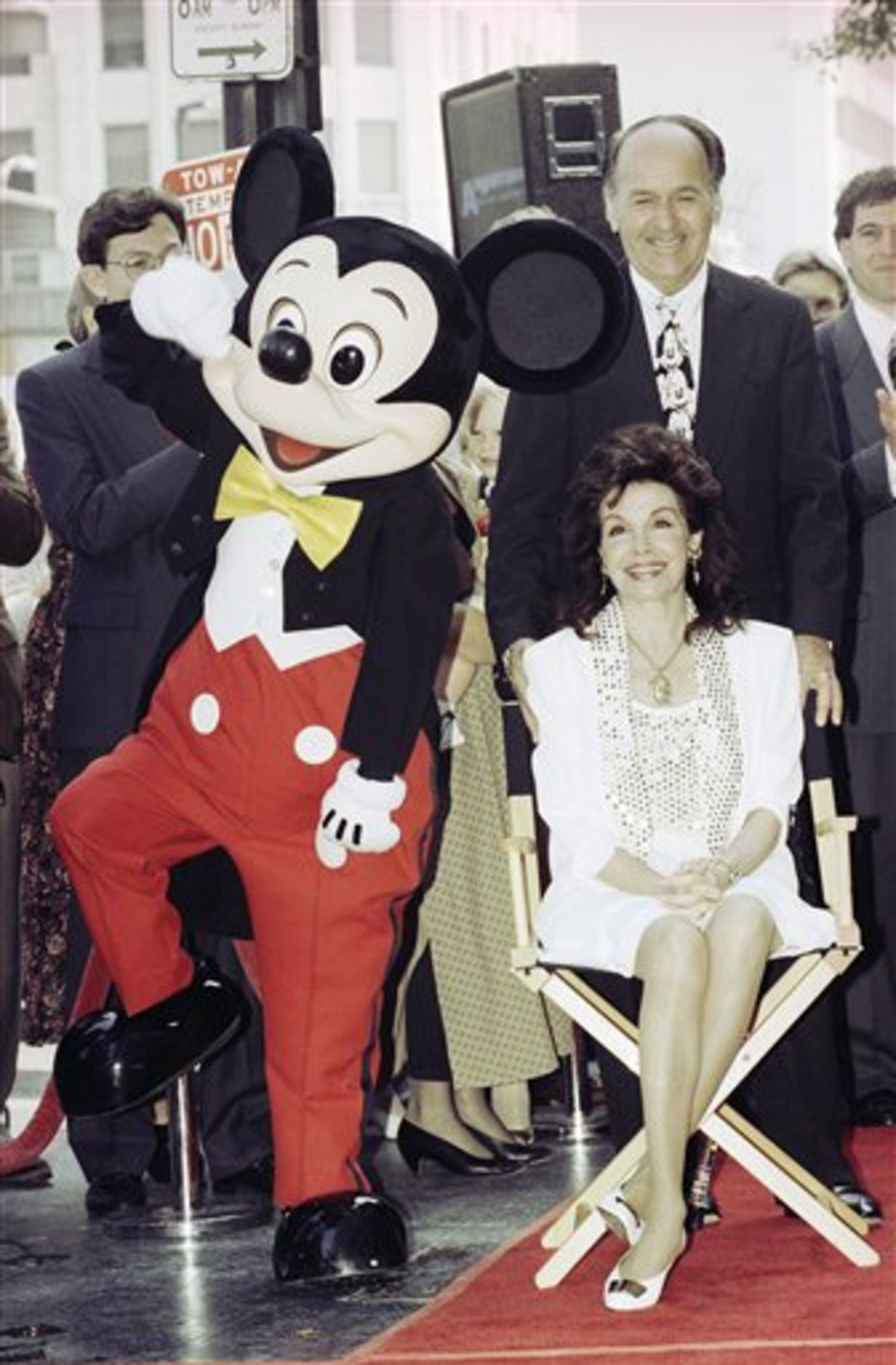 Mickey Mouse dances around as actress and former Mouseketeer Annette Funicello receives a star on the Hollywood Walk of Fame in Los Angeles, Sept. 14, 1993. Behind her is her husband, Glen Holt. Funicello, 50, who has multiple sclerosis, sat in a director's chair throughout the ceremony. (AP Photo/Kevork Djansezian)