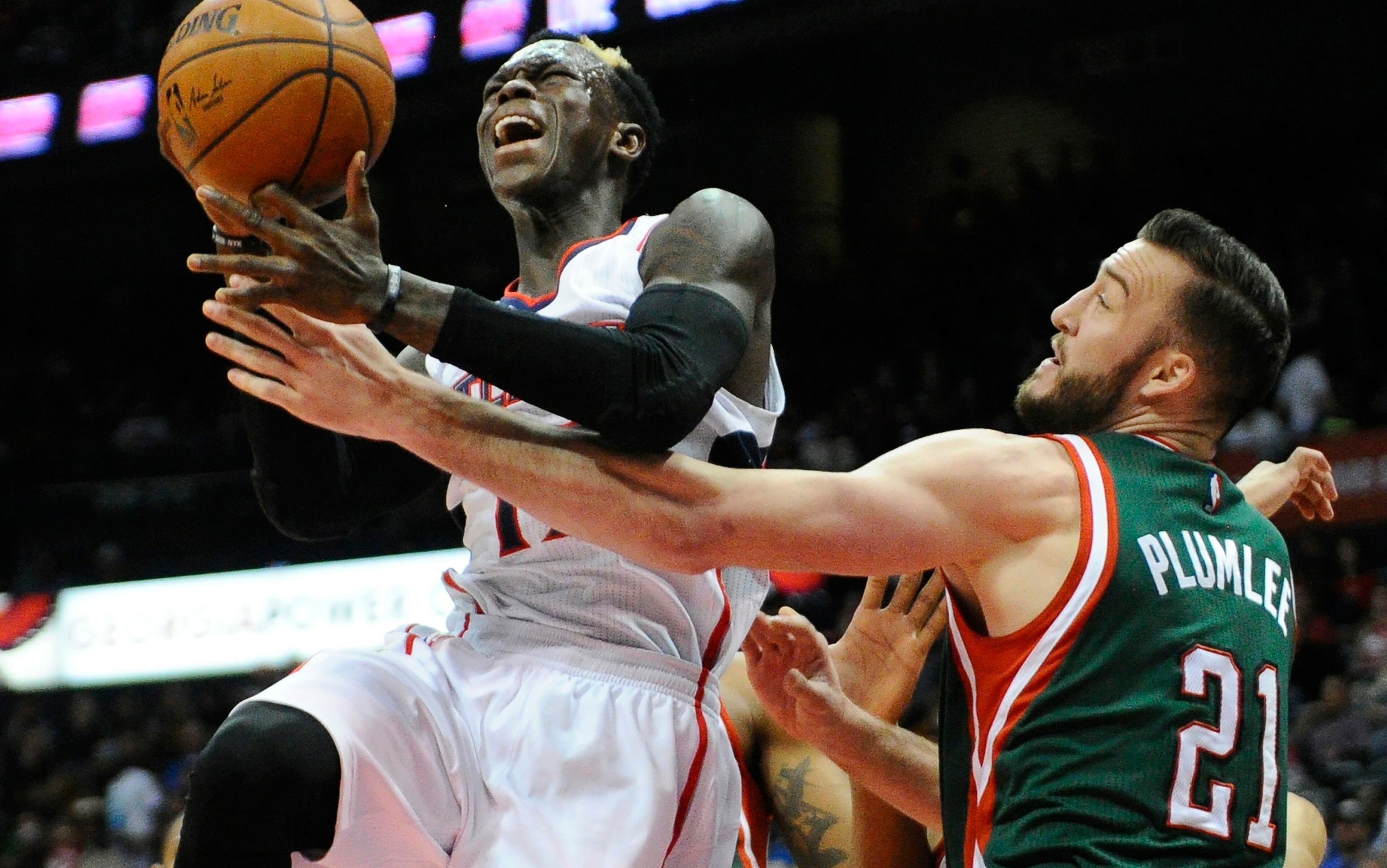 Milwaukee Bucks' Miles Plumlee (21) fouls Atlanta Hawks' Dennis Schroder, left, in the first half of an NBA basketball game Monday, March 30, 2015, in Atlanta. (AP Photo/David Tulis)