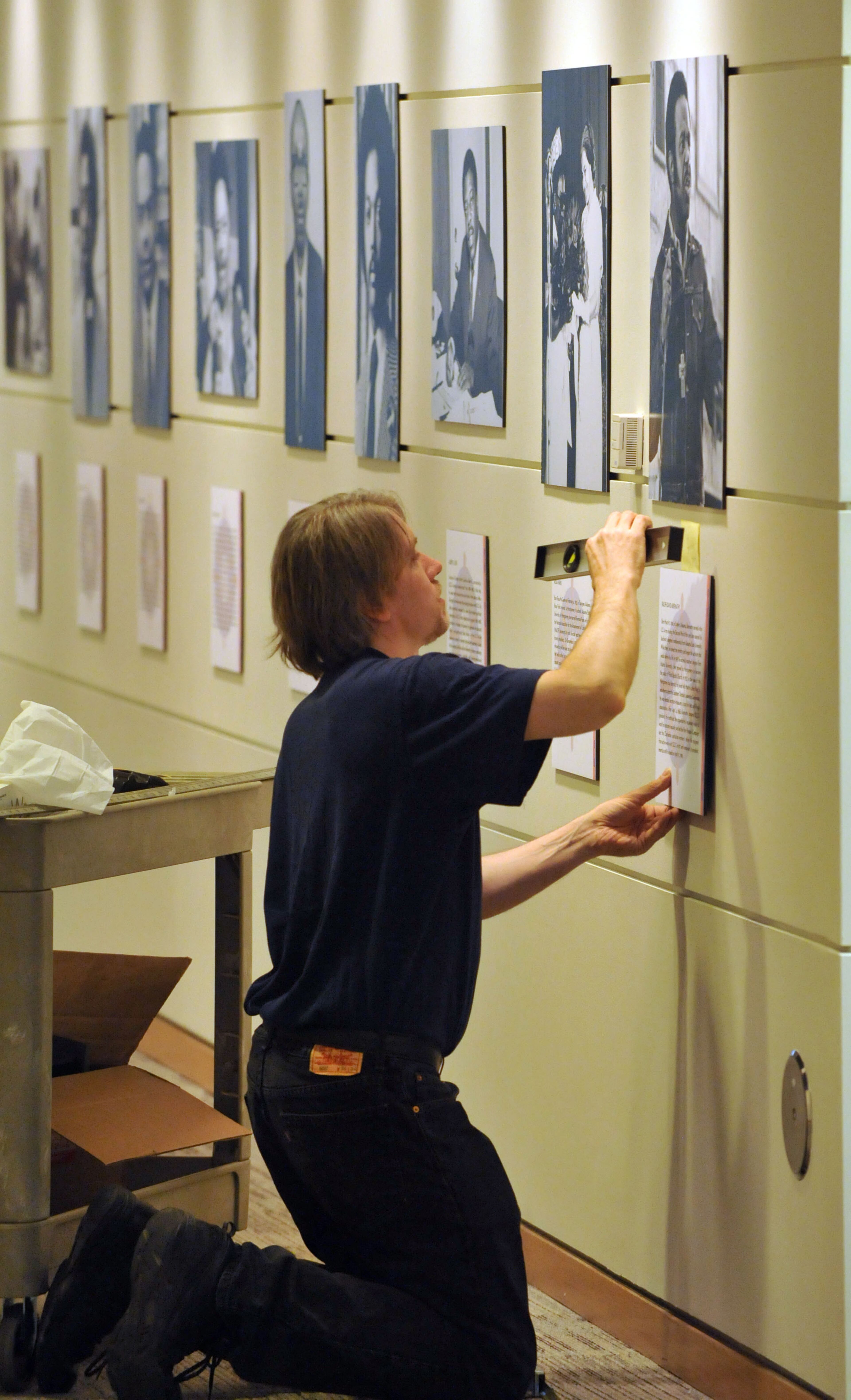 Library staffer John Klingler installs photos in the corridor gallery portion of the exhibit.