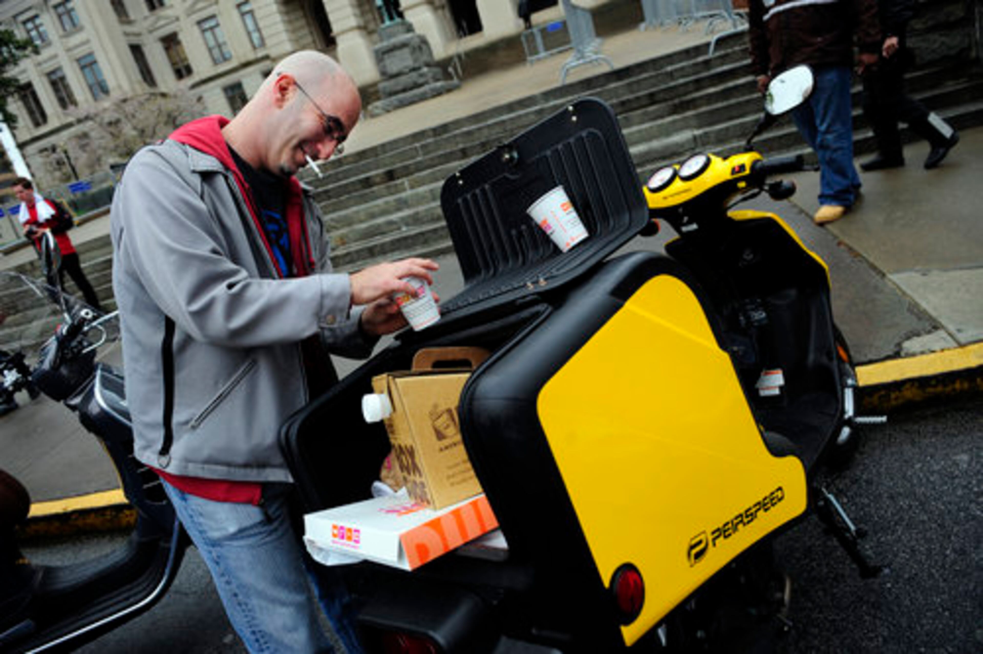 Adam Greenberg, a "renegade" according to his business card, with Eco Moto in Atlanta helps himself to some coffee on the back of a heated delivery scooter.