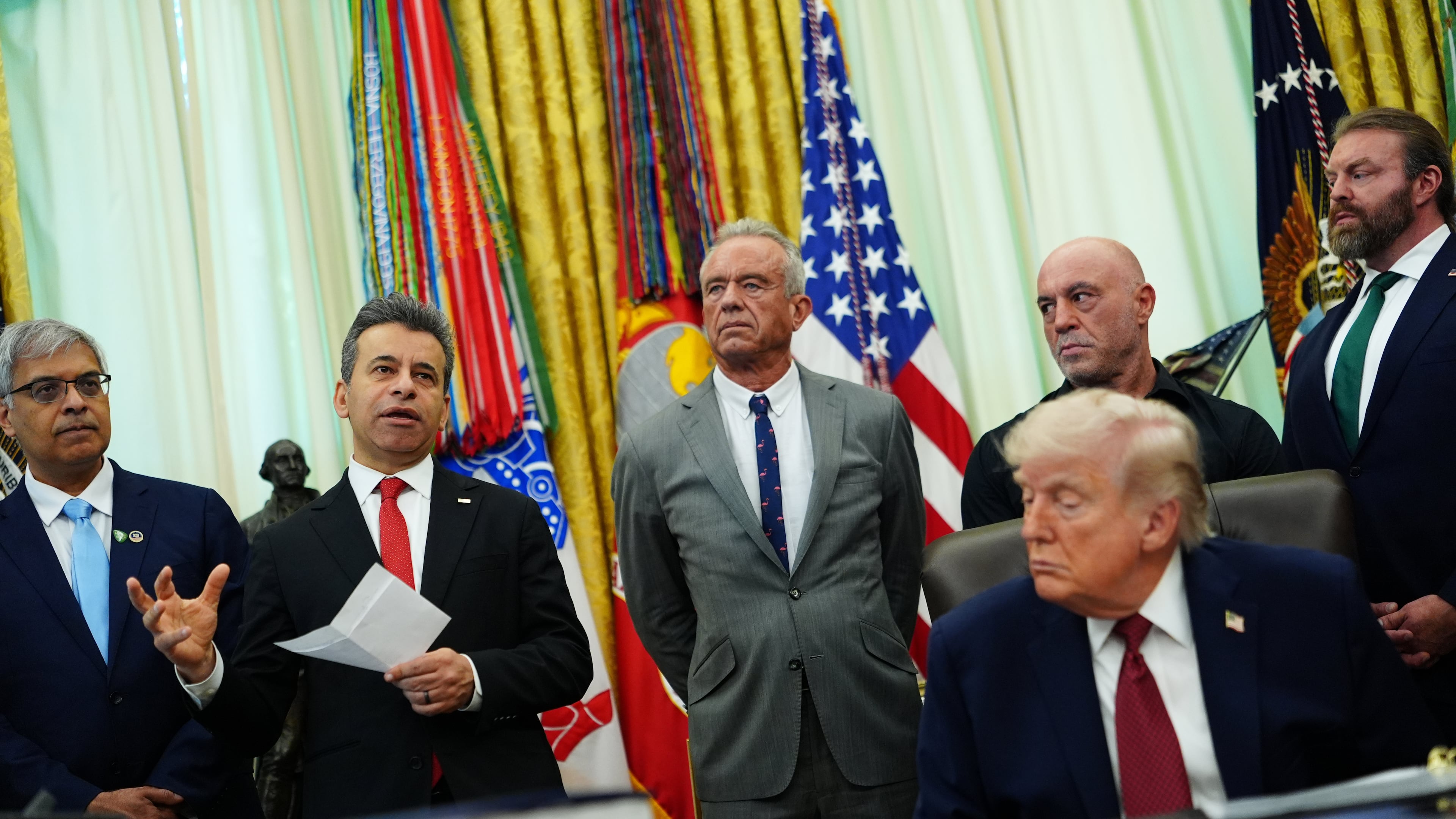 Dr. Marty Makary, commissioner of the Food and Drug Administration, speaks while, from left, National Institutes of Health Director Dr. Jay Bhattacharya, Health and Human Services Secretary Robert F. Kennedy Jr., Joe Rogan, President Donald Trump, Joe Rogan and CEO of Americans for Ibogaine W. Bryan Hubbard listen in the Oval Office of the White House, Saturday, April 18, 2026, in Washington. (AP Photo/Julia Demaree Nikhinson)