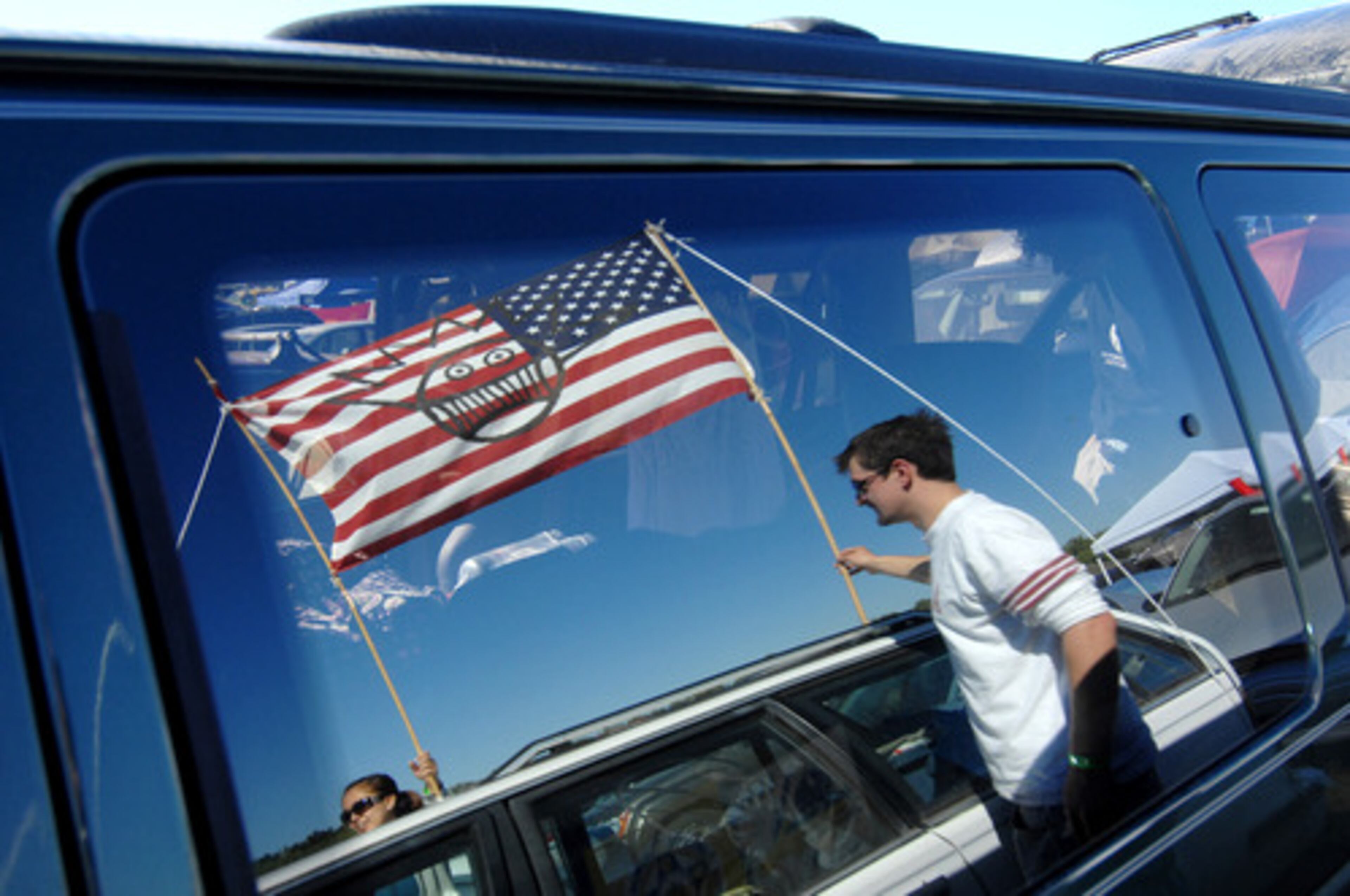 Pat Brooks of Atlanta helps his friends hang a flag on their car in the camping area Thursday. The symbol on the flag is associated with the rock band, Ween.