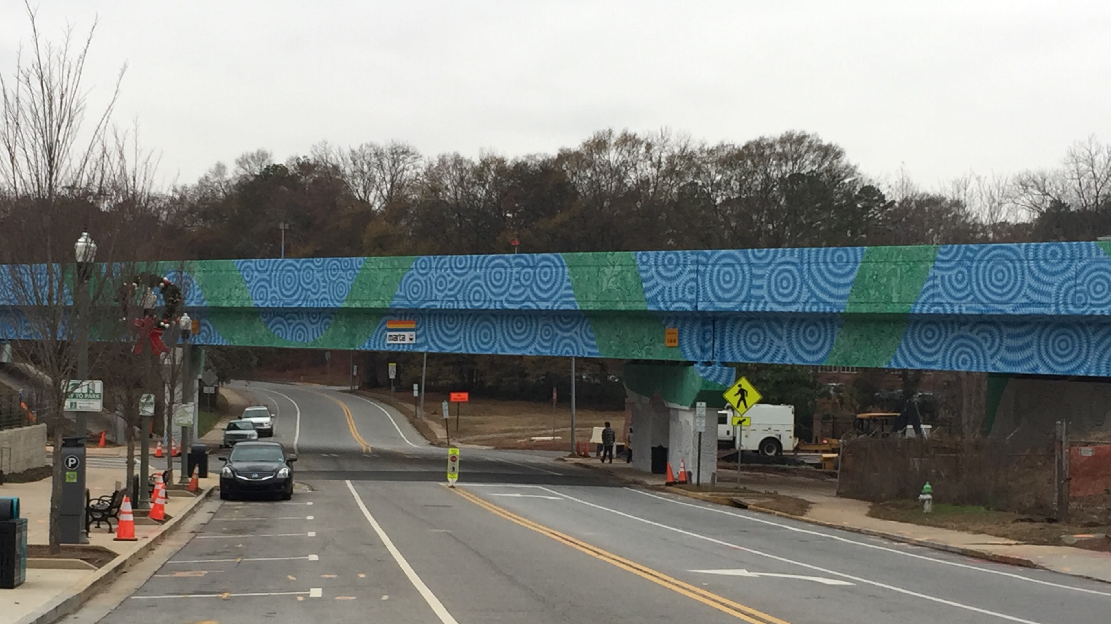Artists Felici Asteinza and Joey Fillastre have mostly completed this side of the MARTA overpass at West Trinity Place and Atlanta Avenue in Decatur. But cold weather and rain have put a temporary halt to the work. On Friday, when this photo was taken, the artists decided they’d return in April to complete the project, which should take another week. Bill Banks for the AJC