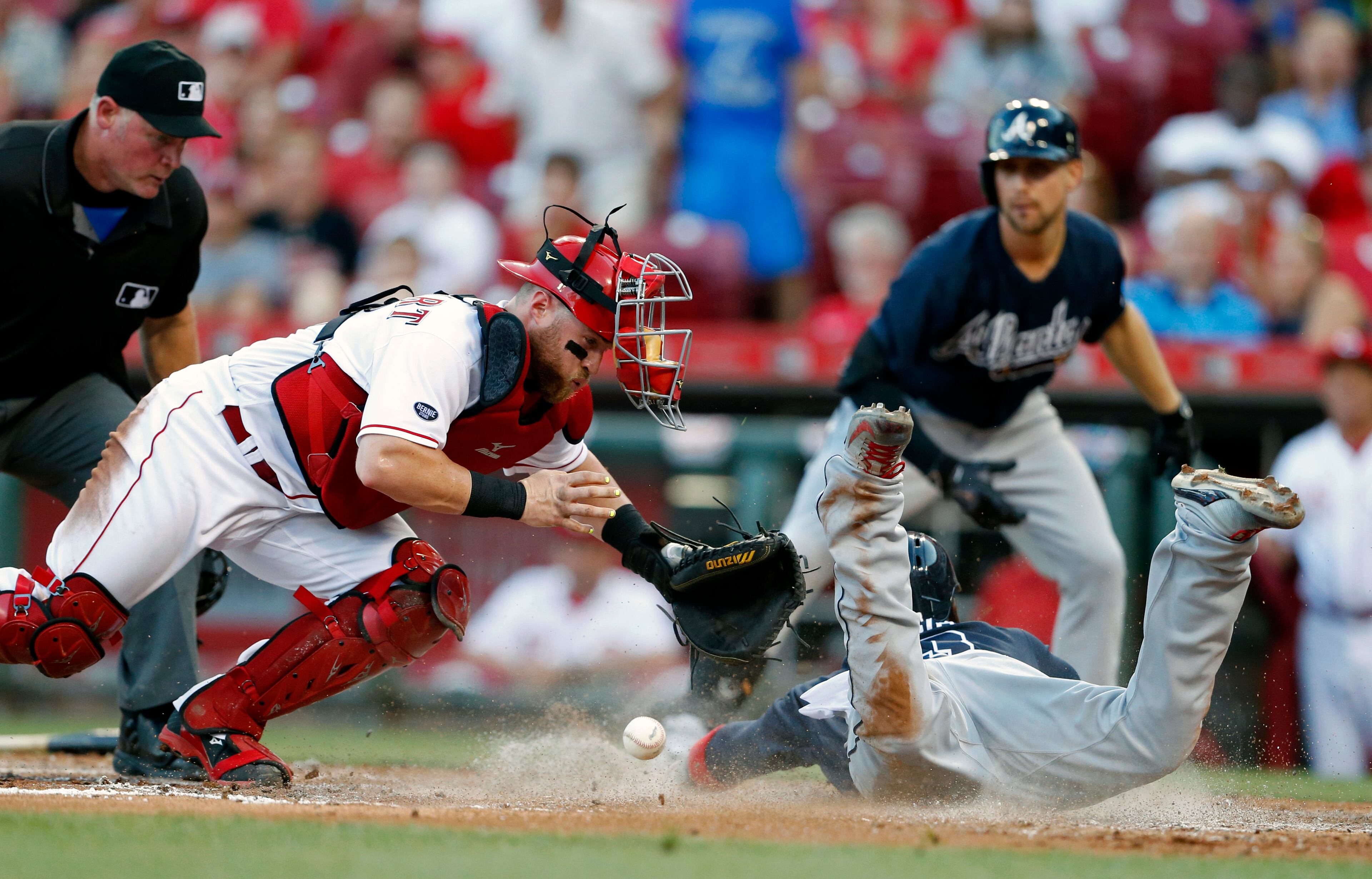 Atlanta Braves' Adonis Garcia, front right, scores as Cincinnati Reds catcher Tucker Barnhart , front left, loses the ball during the fourth inning of a baseball game, Monday, July 18, 2016, in Cincinnati. (AP Photo/Gary Landers)