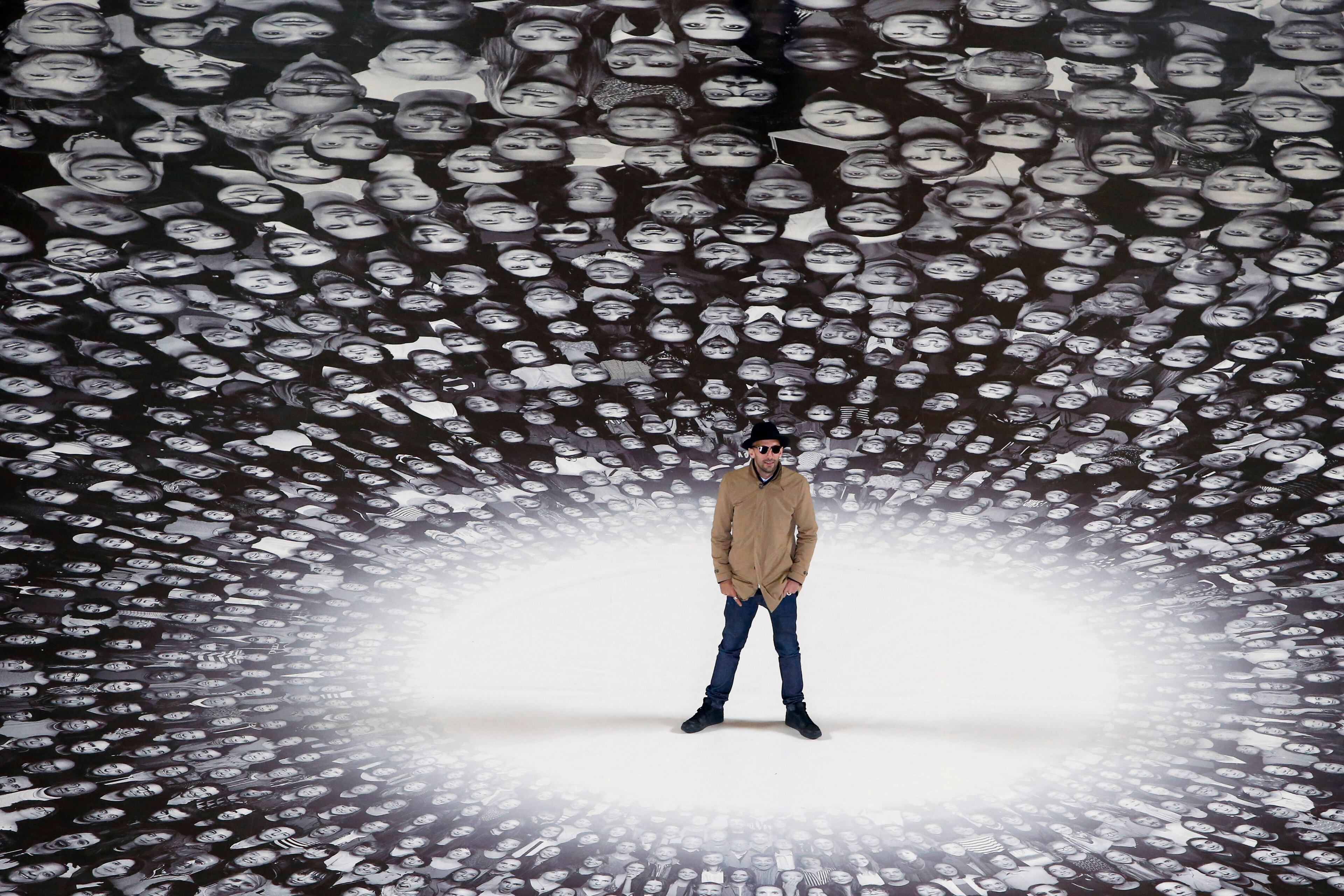 French street artist and photographer JR poses on his creation during the presentation to the press at the Pantheon in Paris, Tuesday, June 3, 2014. French Government named JR to decorate with portraits of Paris' Pantheon, that is the final resting place for 72 of France's renowned men, and just one woman, as the monument is undergoing a 2 year renovation. (AP Photo/Francois Mori)