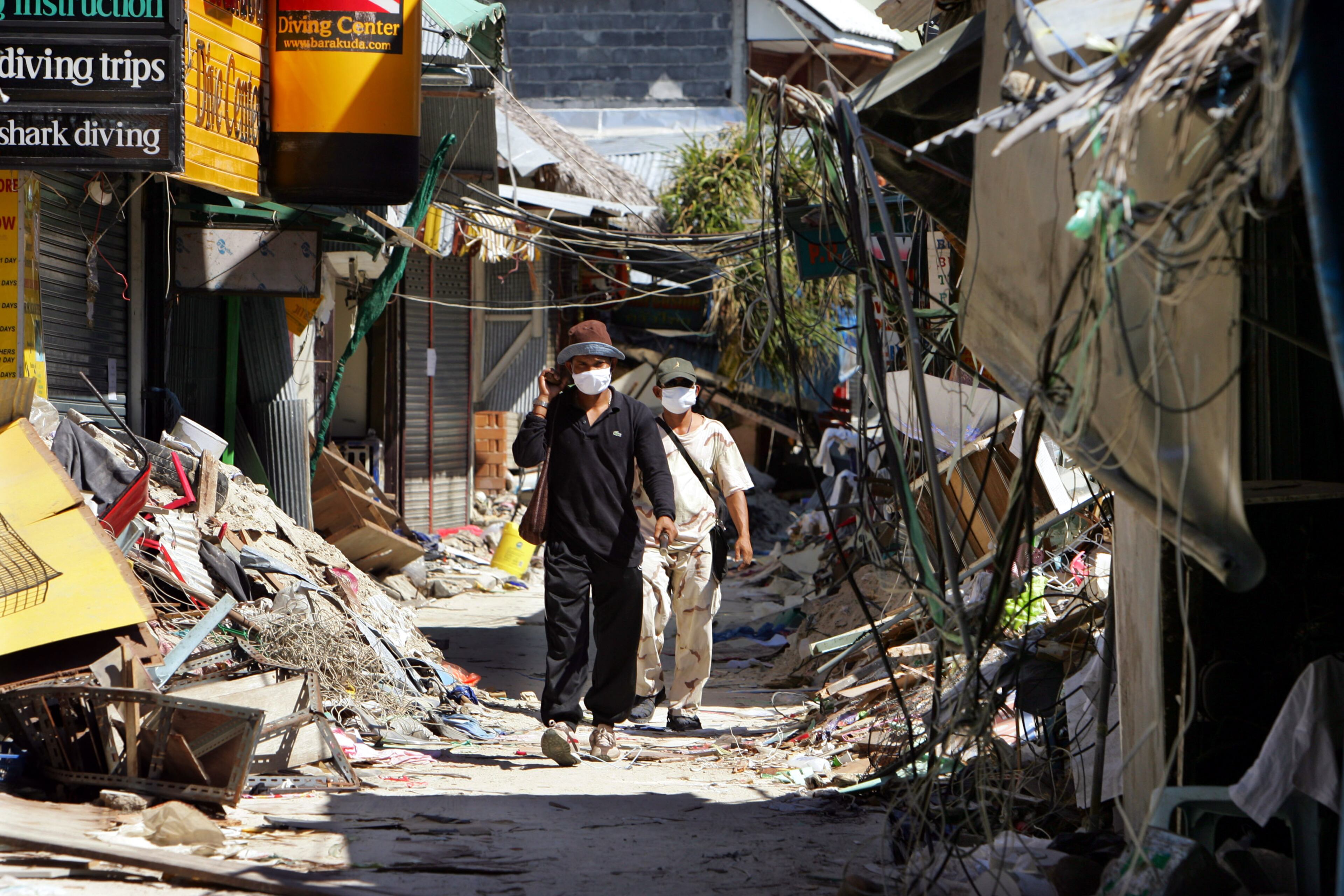 KOH PHI PHI ISLAND, THAILAND - JANUARY 25: People walks through the streets of Tsunami-damaged Phi Phi Village January 25, 2005 almost one month after the devastating Tsunami hit Ton Sai Bay in Kho Phi Phi, Thailand. Many are still missing after the waves slammed into Phi Phi village where many hotels, restaurants and shops were destroyed. Current figures put the death toll over 200,000 claiming victims in a dozen countries with over 5,000 deaths in Thailand alone. (Photo by Paula Bronstein/Getty Images)